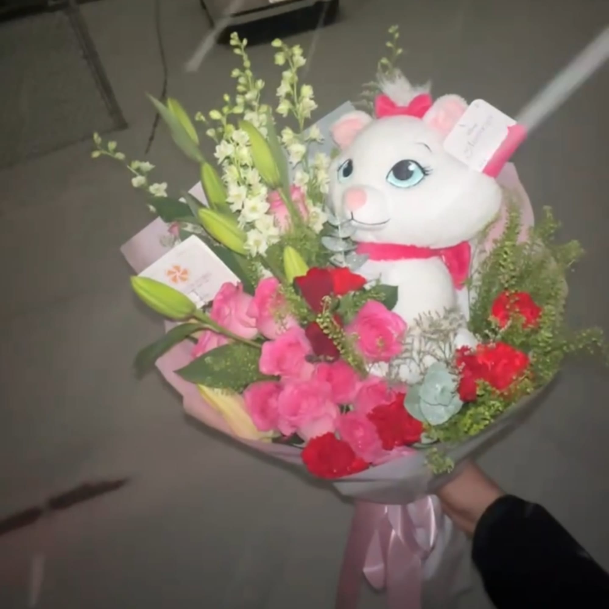 Bouquet of pink and red flowers with a white plush cat