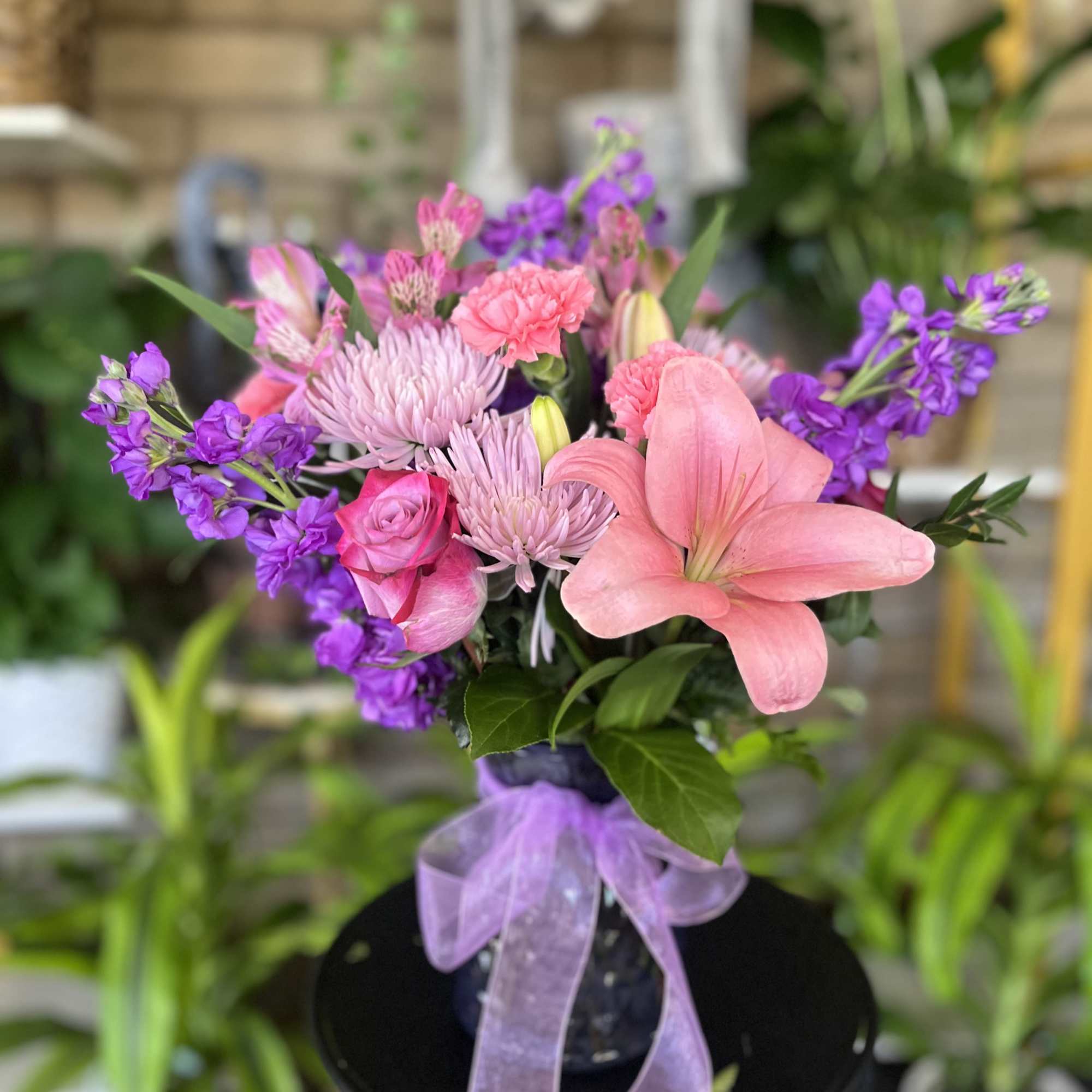 Pink and purple bouquet in a vase with a lavender ribbon
