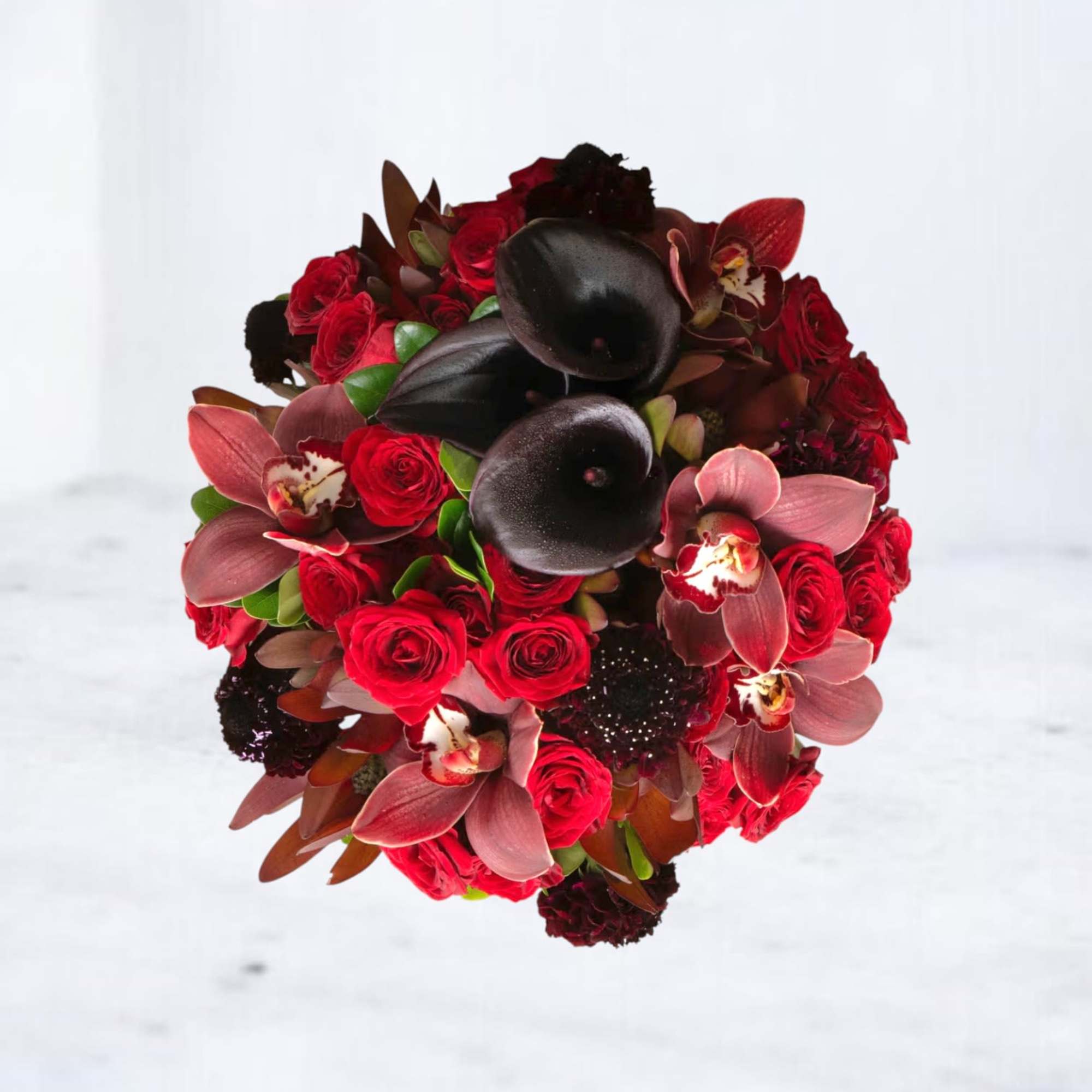 Round hand-tied bouquet of deep red roses, pink orchids, and near-black calla lilies.