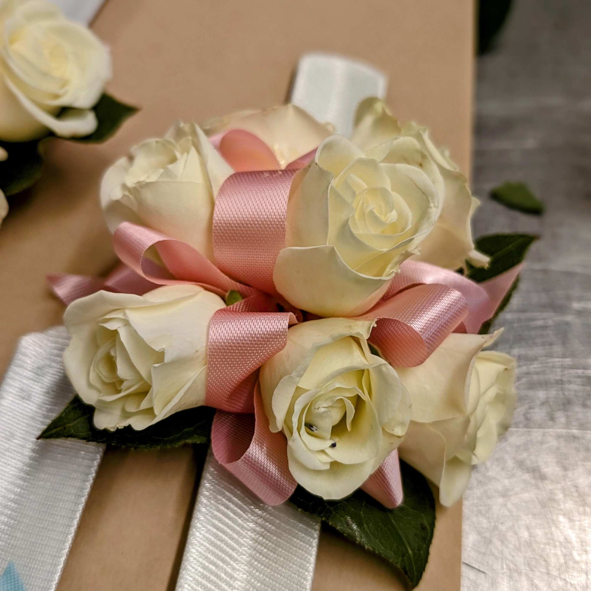 Tight cluster of white roses with ribbon color accent on a snap