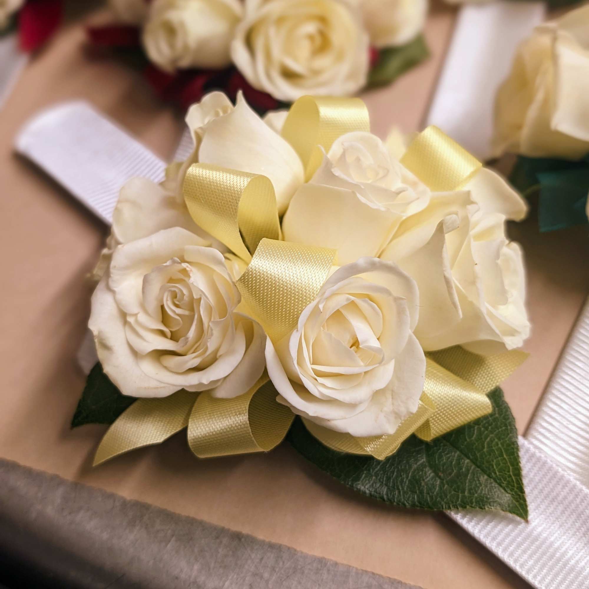 Tight cluster of white roses with ribbon color accent on a snap