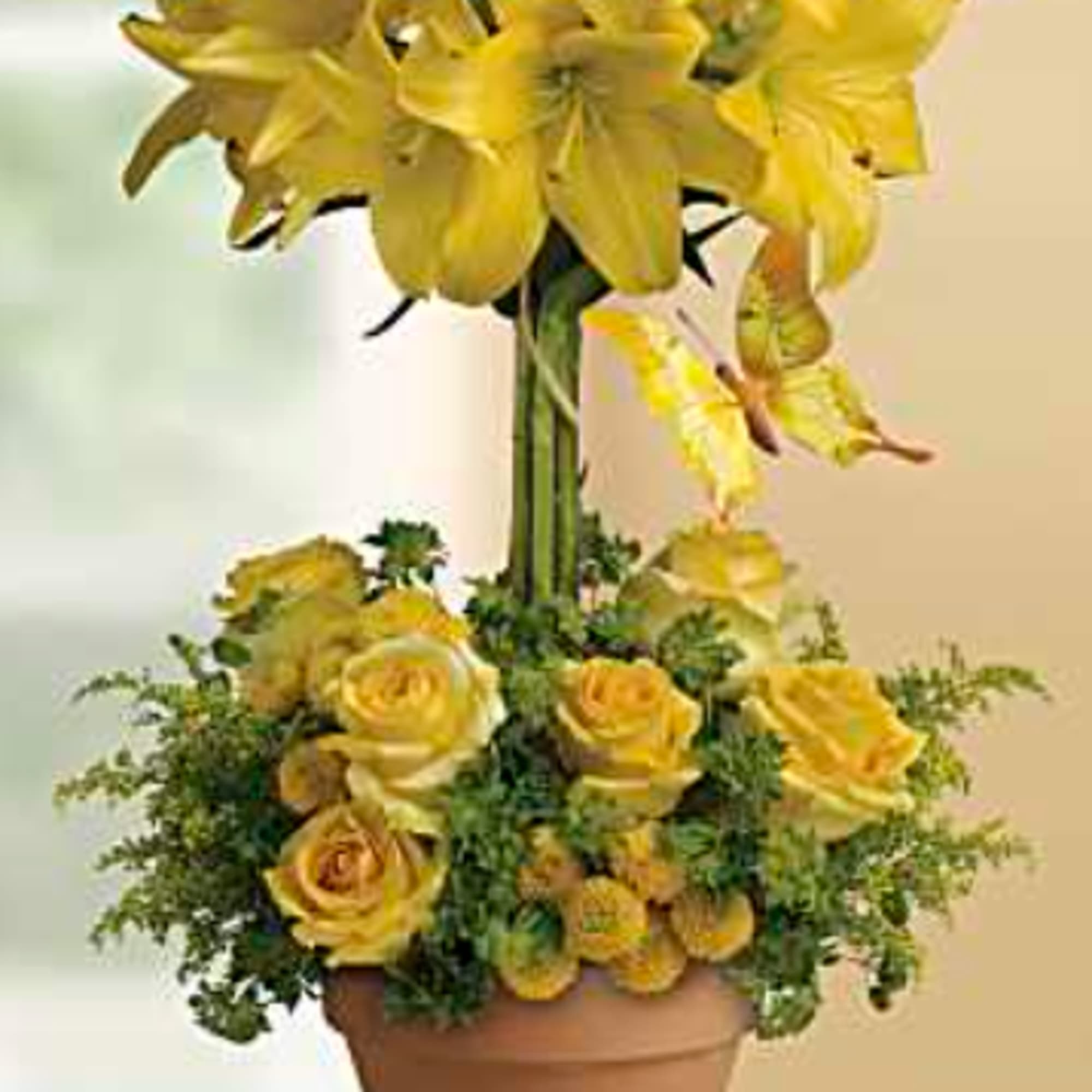 Sunlit yellow lilies tower above a compact mound of yellow roses in