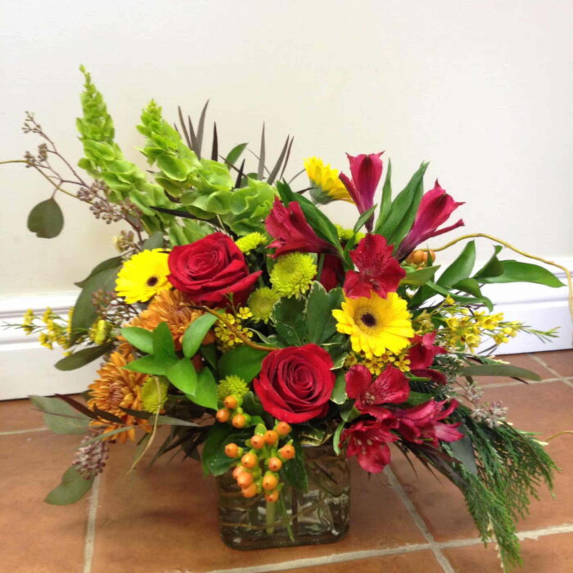 Mixed bouquet of red roses and yellow daisies in a glass vase