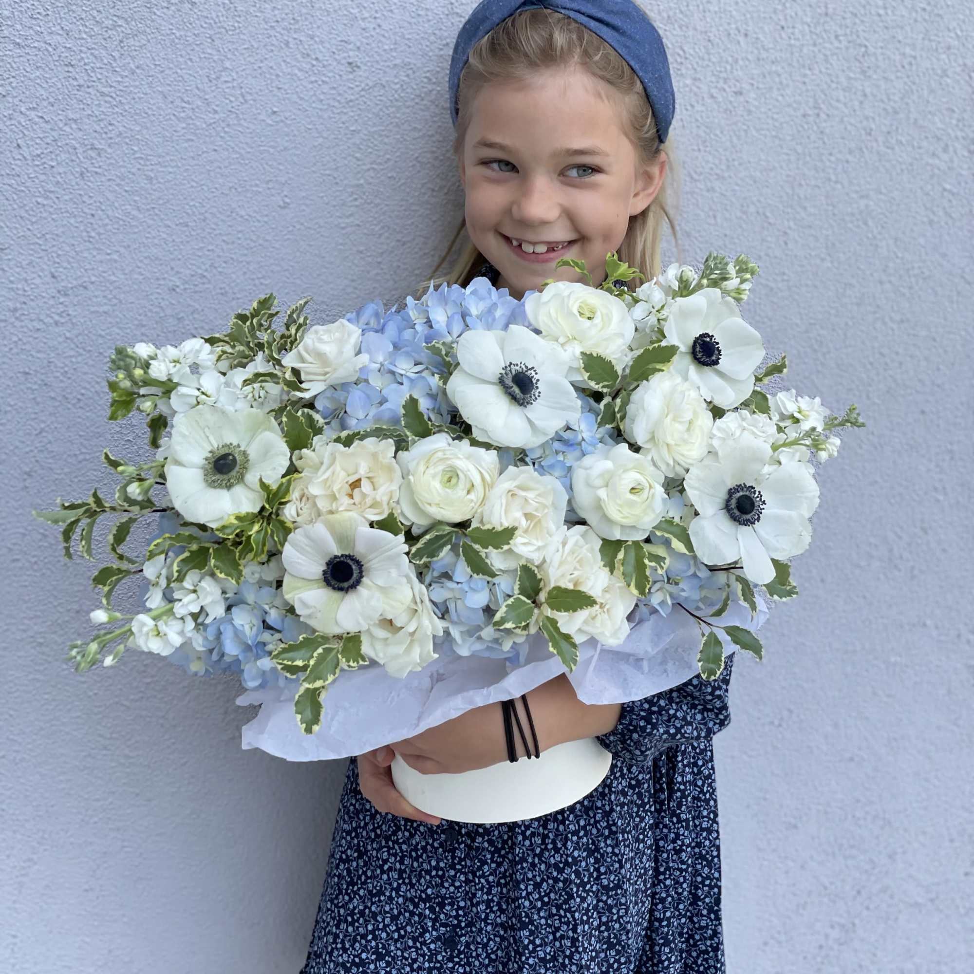 Girl holding a large bouquet of white and pale blue flowers