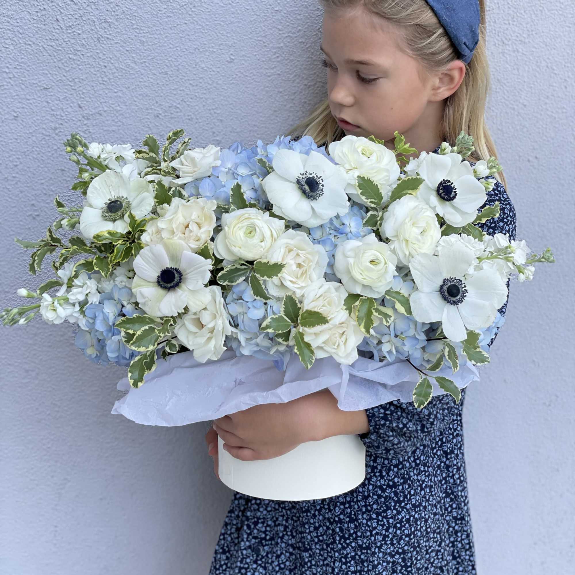 Girl holding a white and pale blue bouquet in a white box