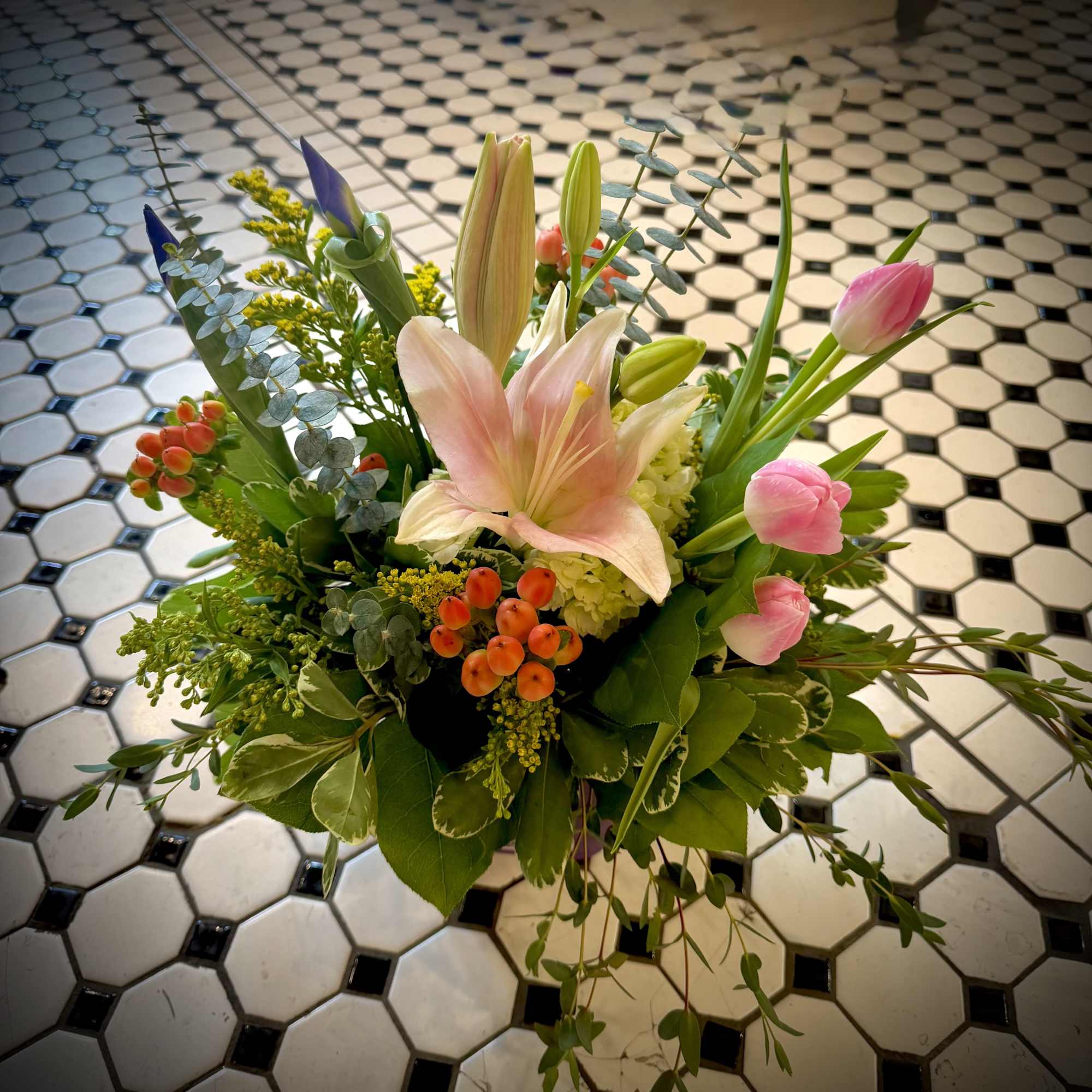 A cluster of soft pink lilies and tulips opens like a gentle