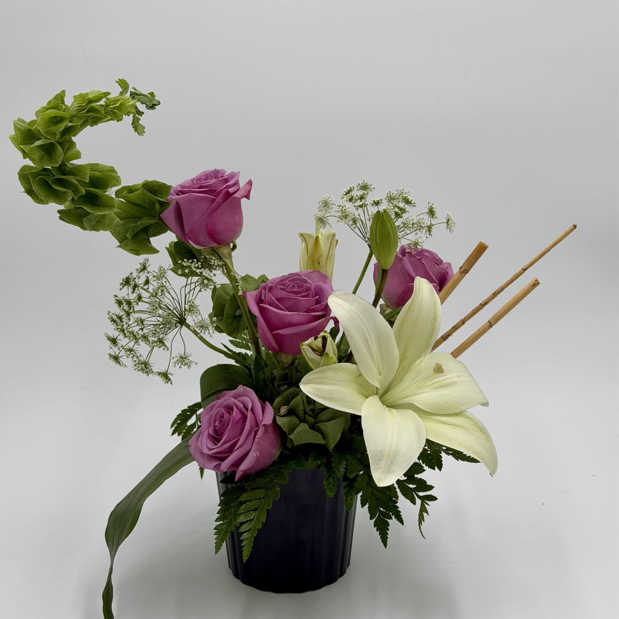 A graceful blend of lavender roses and elegant white lilies creates a