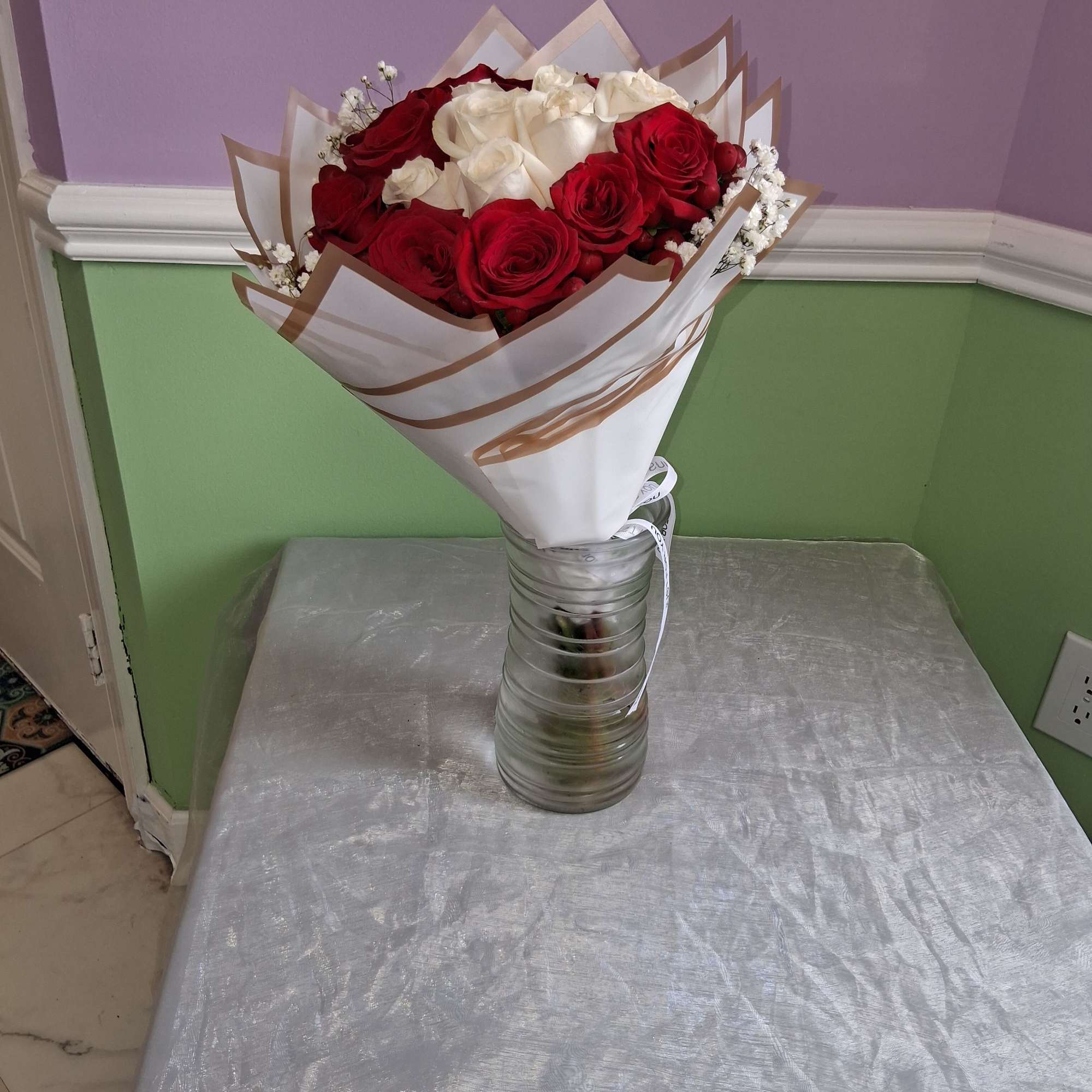 A striking ring of deep red roses encircles a creamy white heart