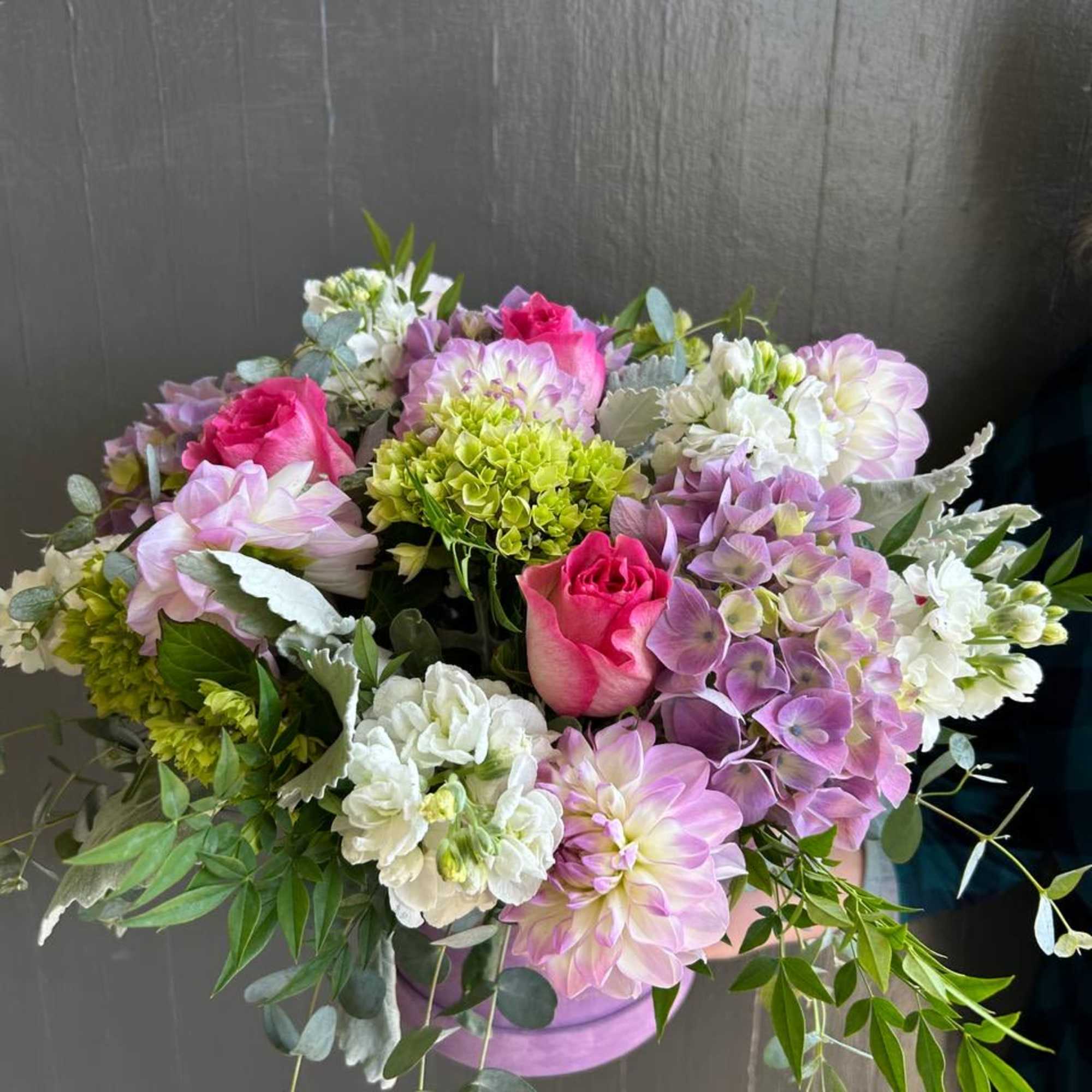 Bouquet of pink roses, lavender dahlias, and white blooms in a lavender container
