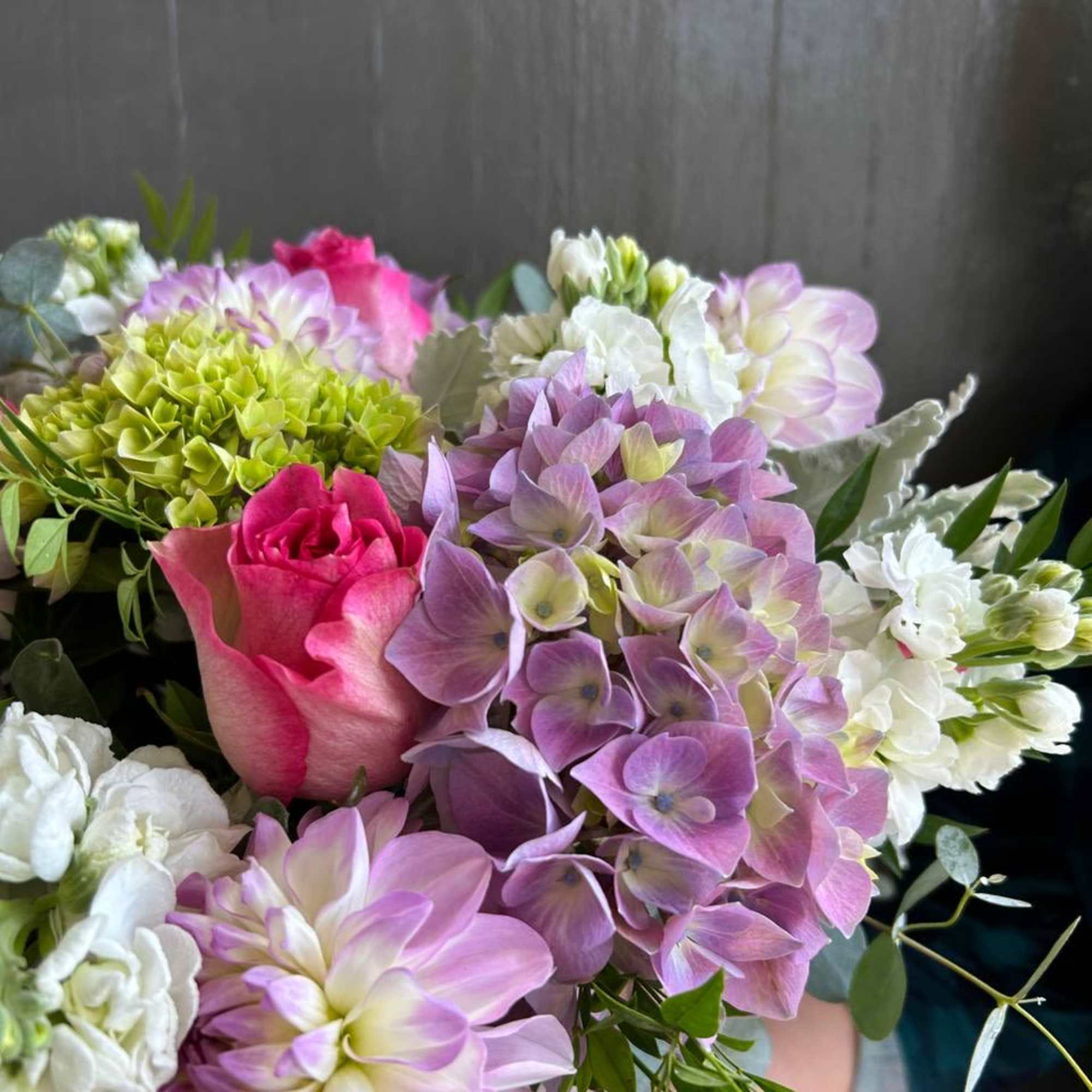 Bouquet of pink and lavender flowers with white blooms and a green hydrangea cluster