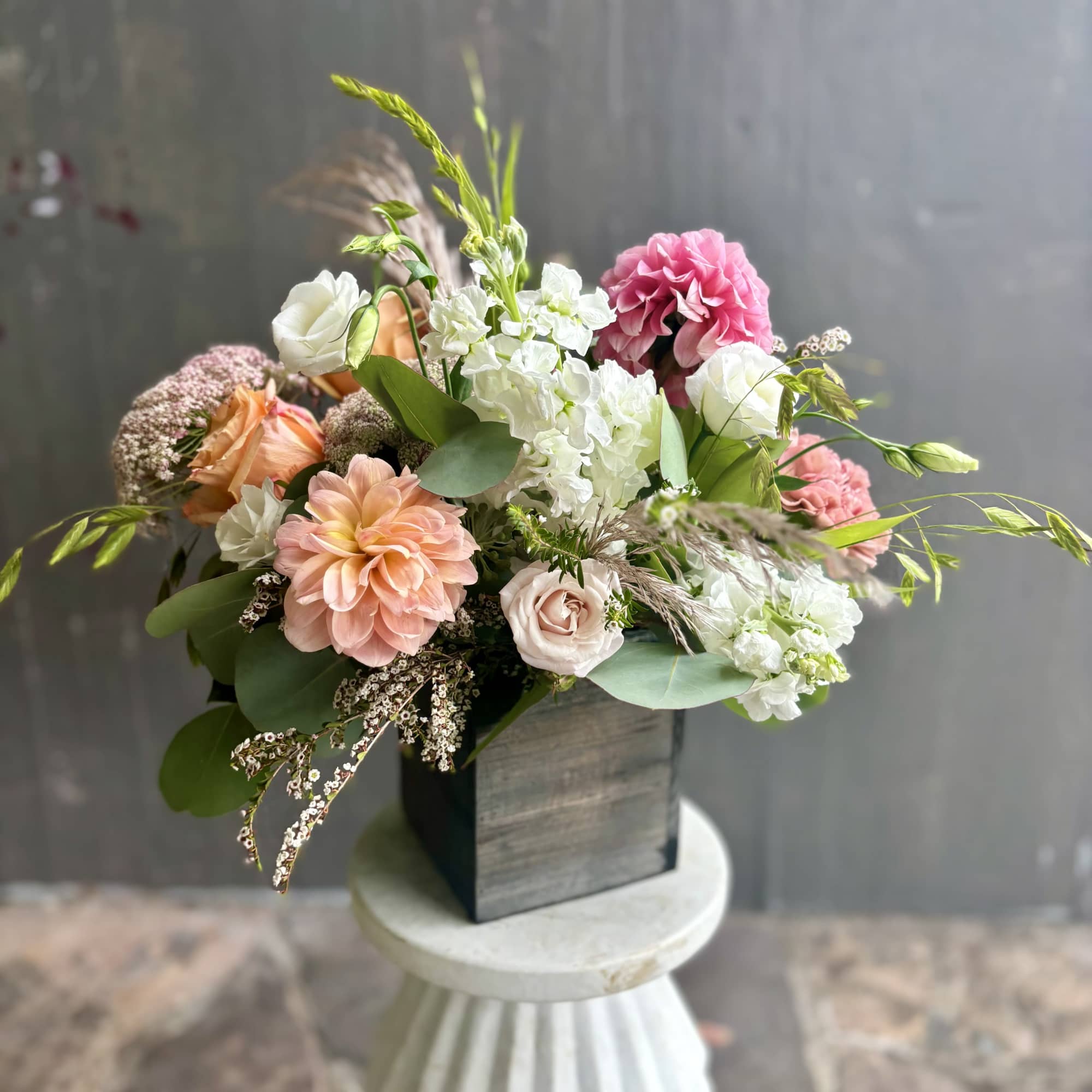 Mixed bouquet in a dark square vase with pink, white, and peach flowers