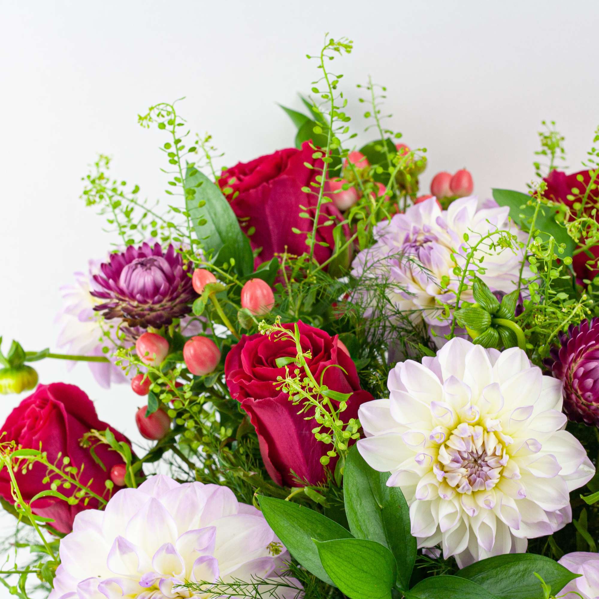 Bouquet of red roses, white dahlias, and purple blooms with airy greenery