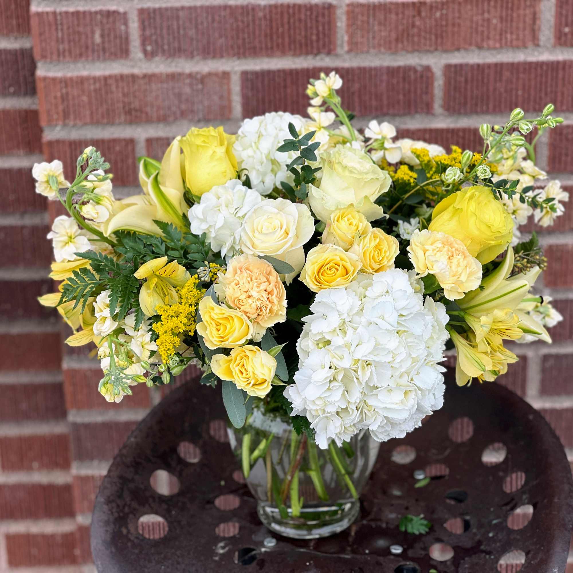 Yellow and white mixed flower bouquet in a clear glass vase