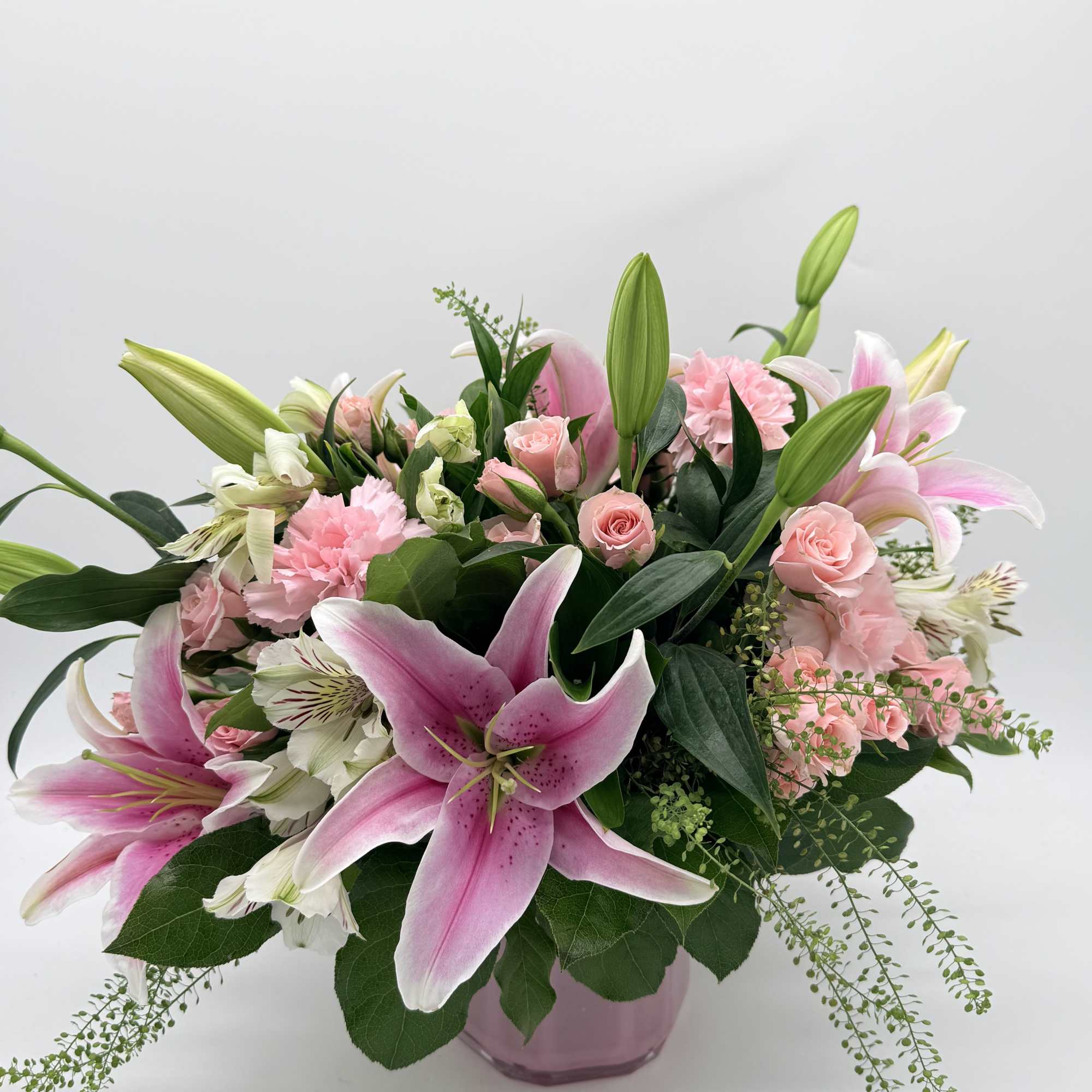 Large pink lilies burst open above a cloud of soft pink roses