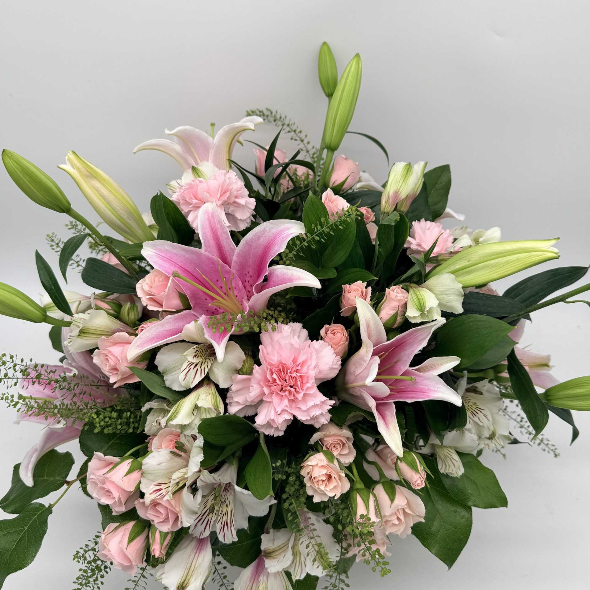 Large pink lilies burst open above a cloud of soft pink roses