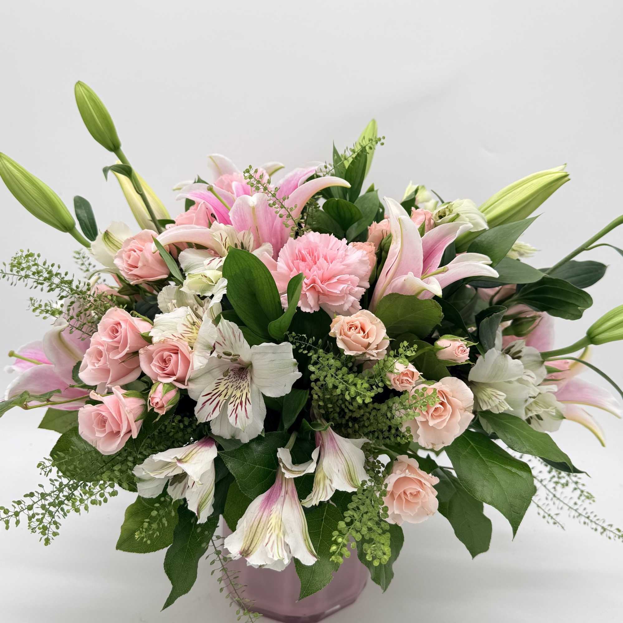 Large pink lilies burst open above a cloud of soft pink roses
