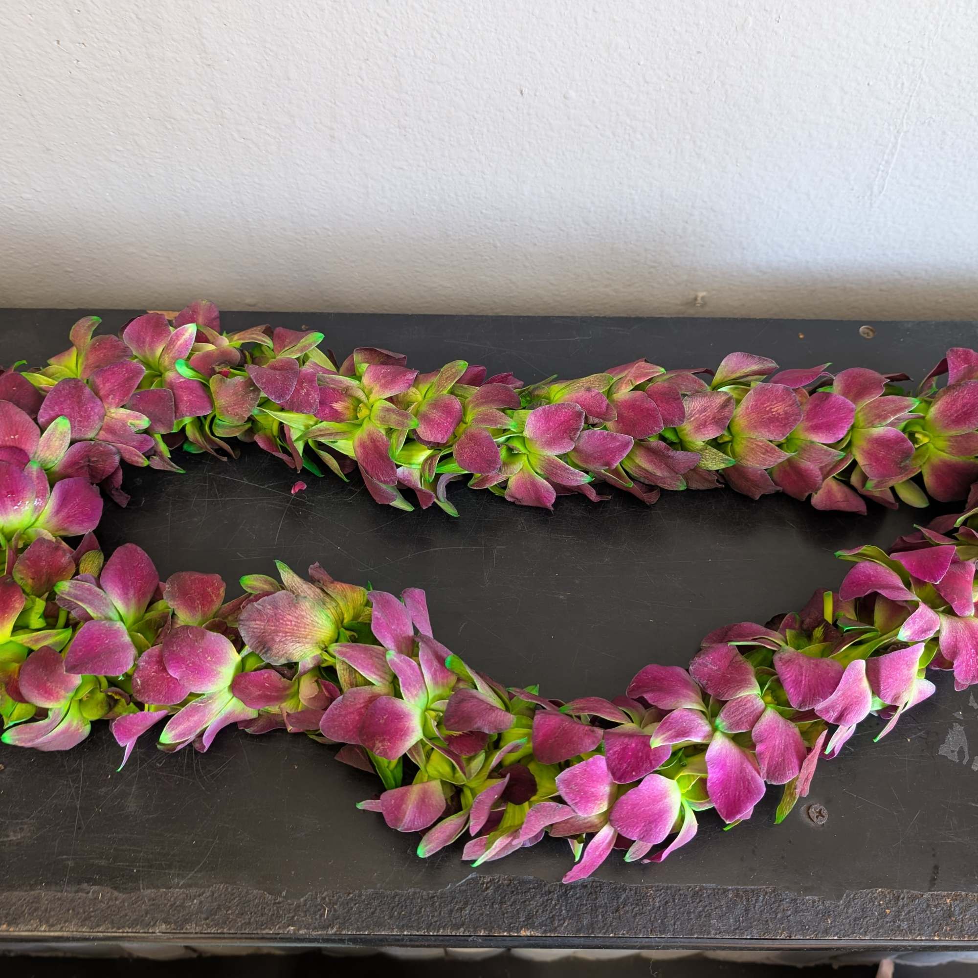 Pink and green flower lei laid in a loop