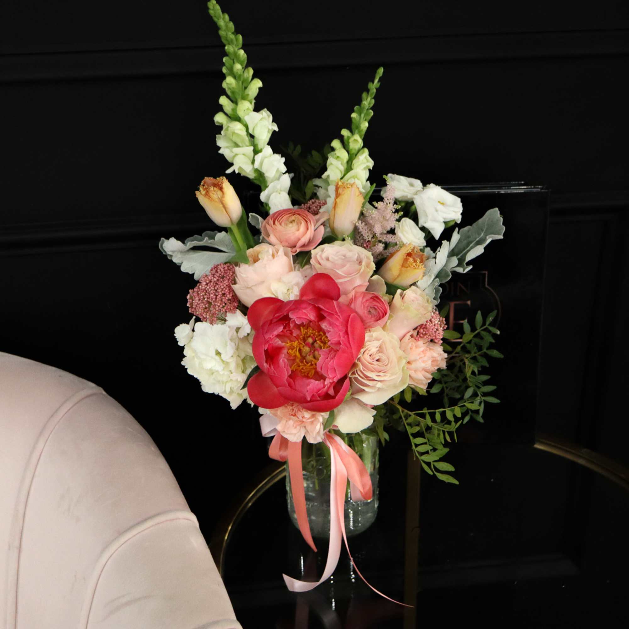 Mixed pink and white flowers in a clear glass vase with ribbon