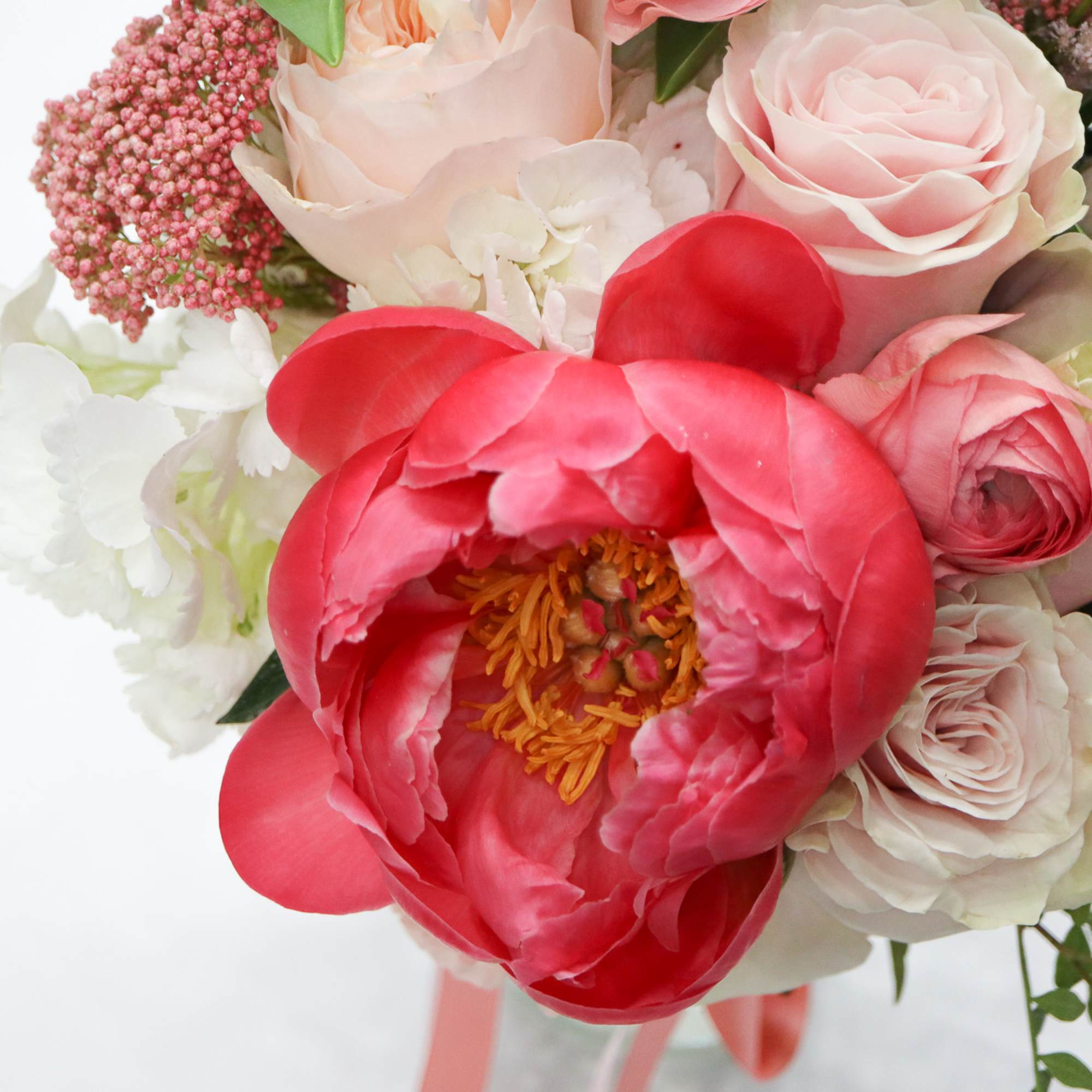 Bouquet of pink and white roses with a large coral peony