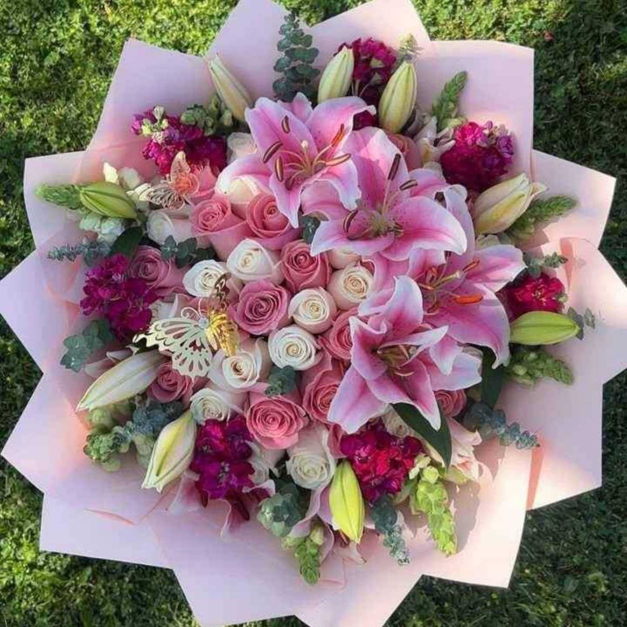 A lush, hand-tied floral bouquet built around classic roses and lilies-BUCHONES is