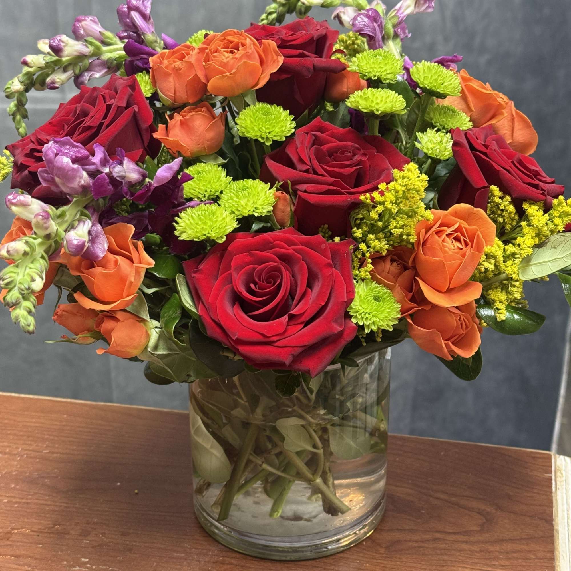 Mixed bouquet of red, orange, and purple flowers in a glass vase
