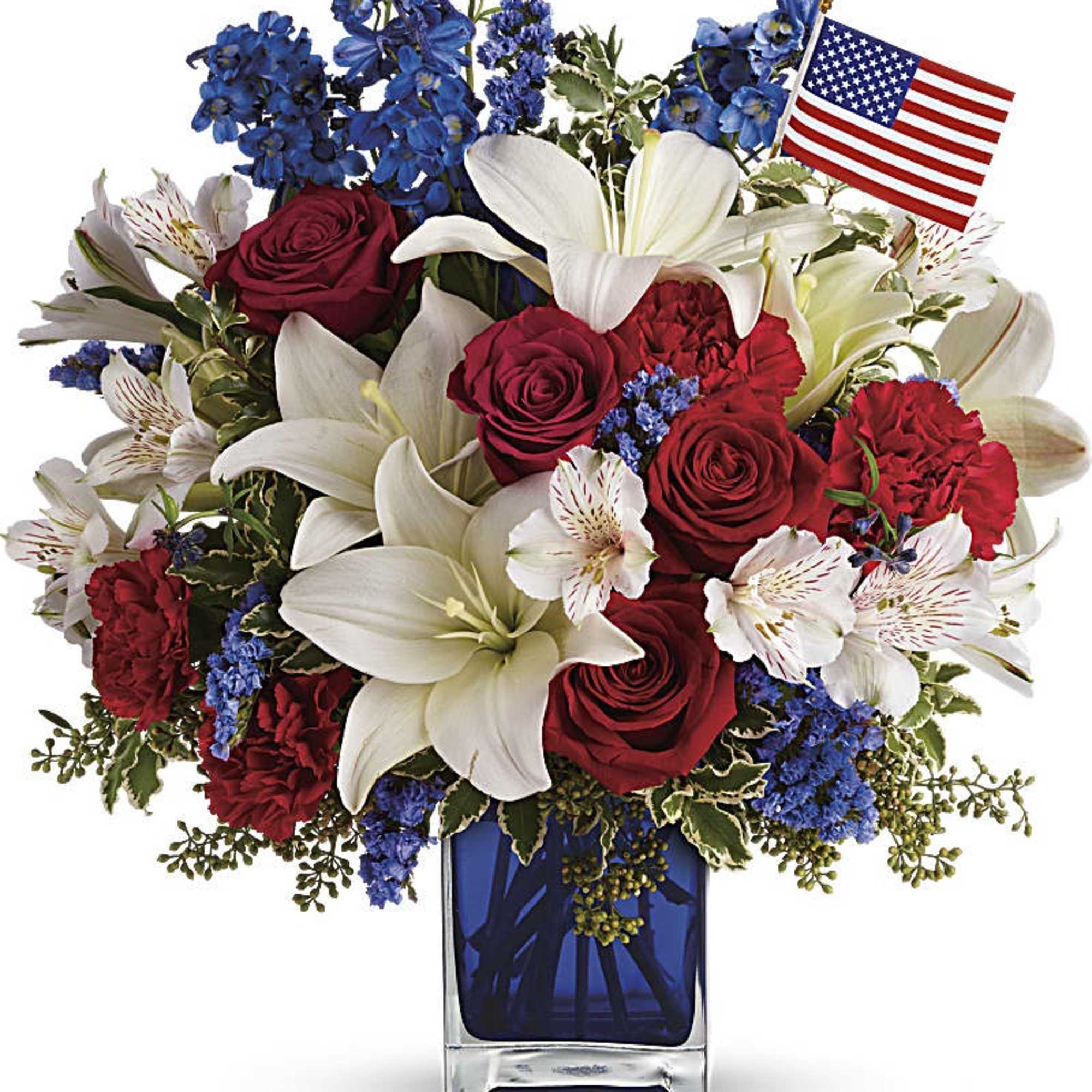 Red, white, and blue flower arrangement with an American flag in a blue glass vase