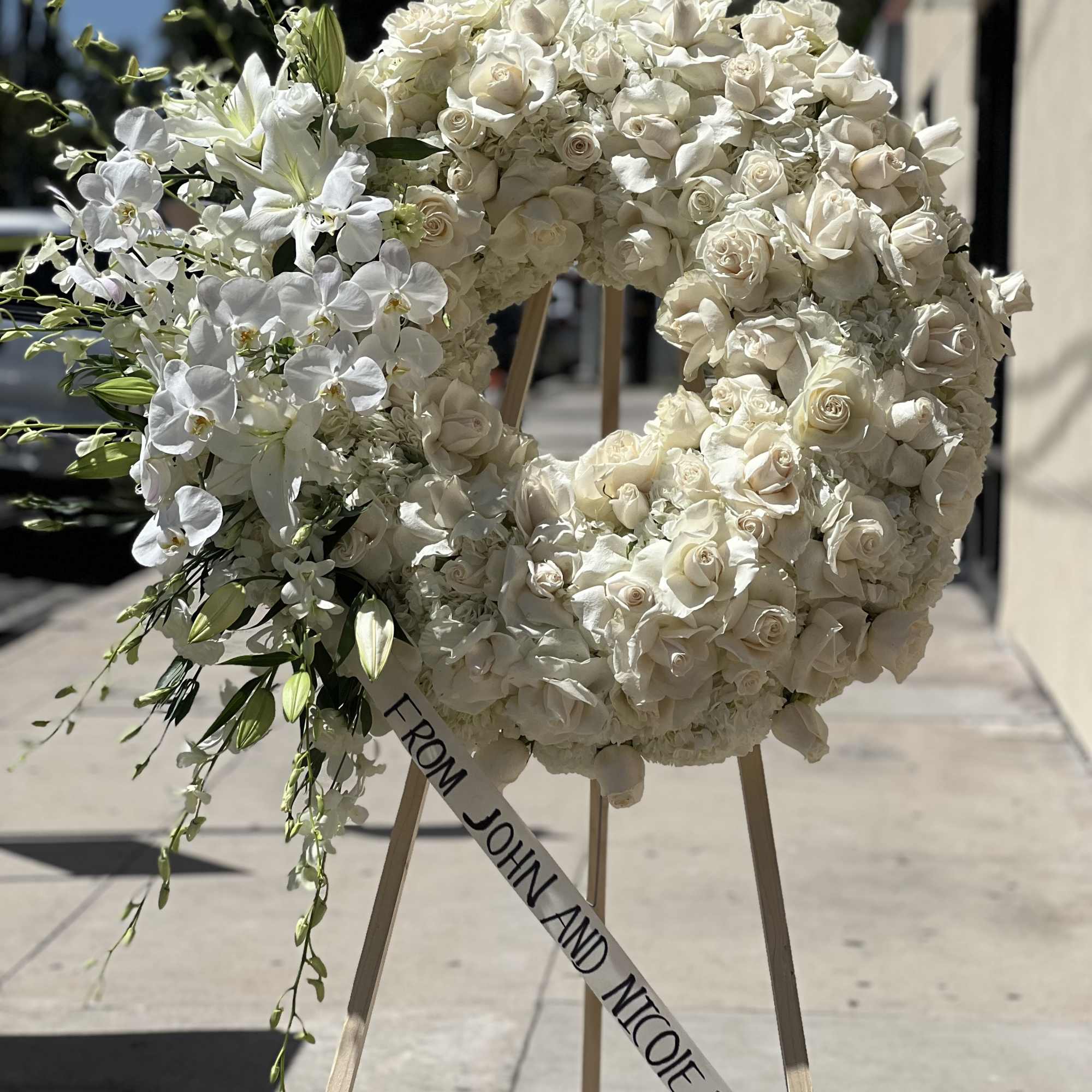 White rose and orchid funeral wreath on a stand