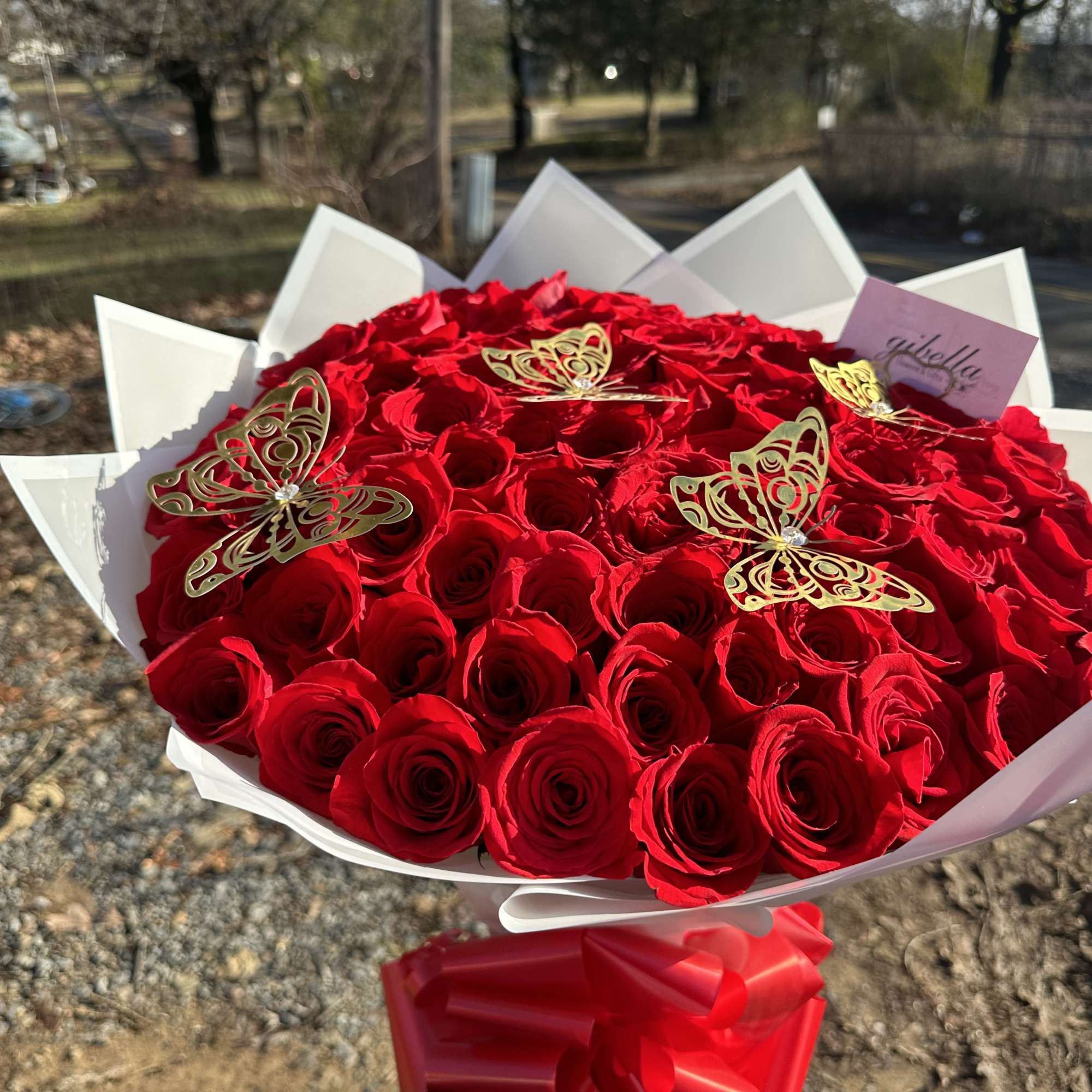Large bouquet of red roses with gold butterfly accents and a red ribbon
