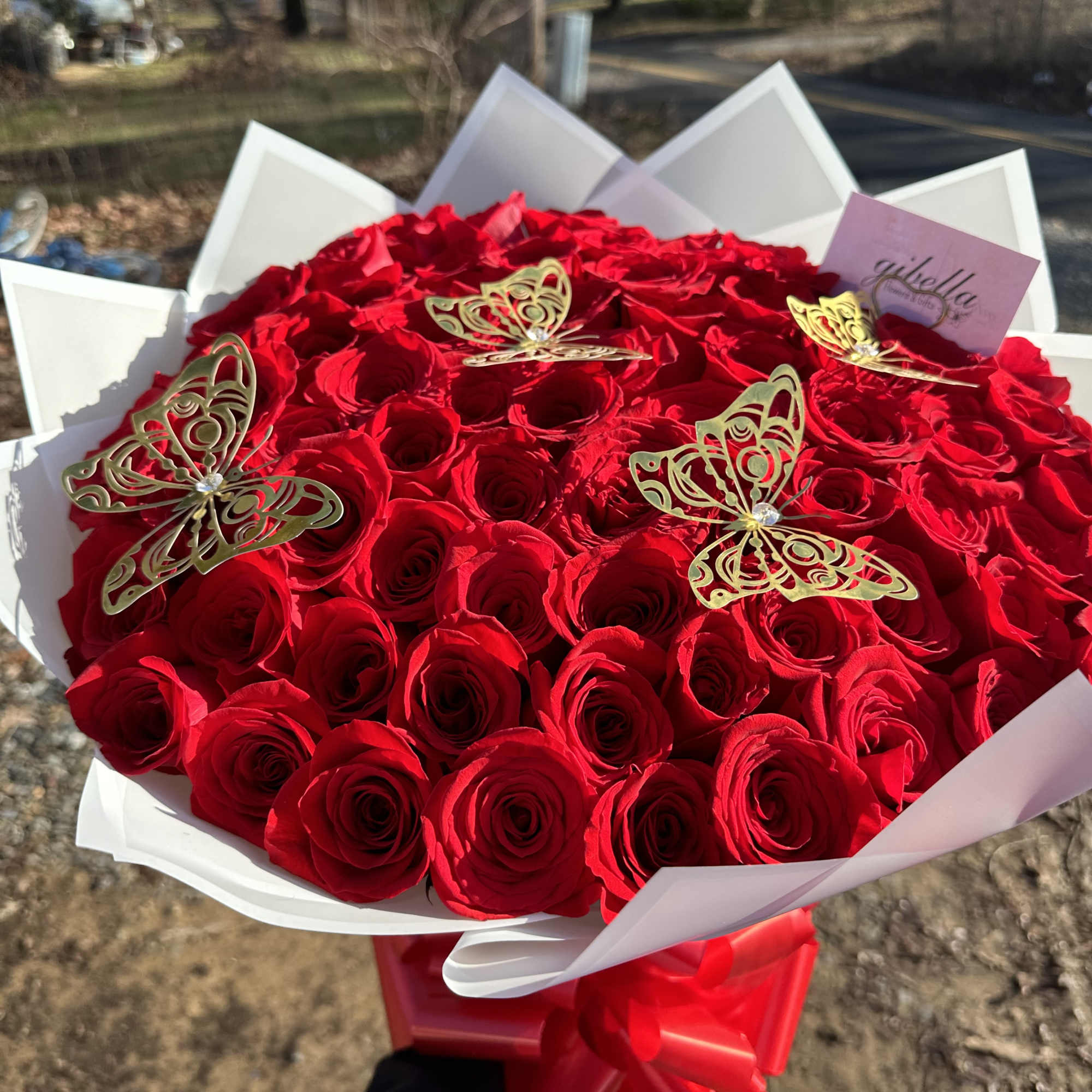 Large bouquet of red roses with gold butterfly picks and white wrap