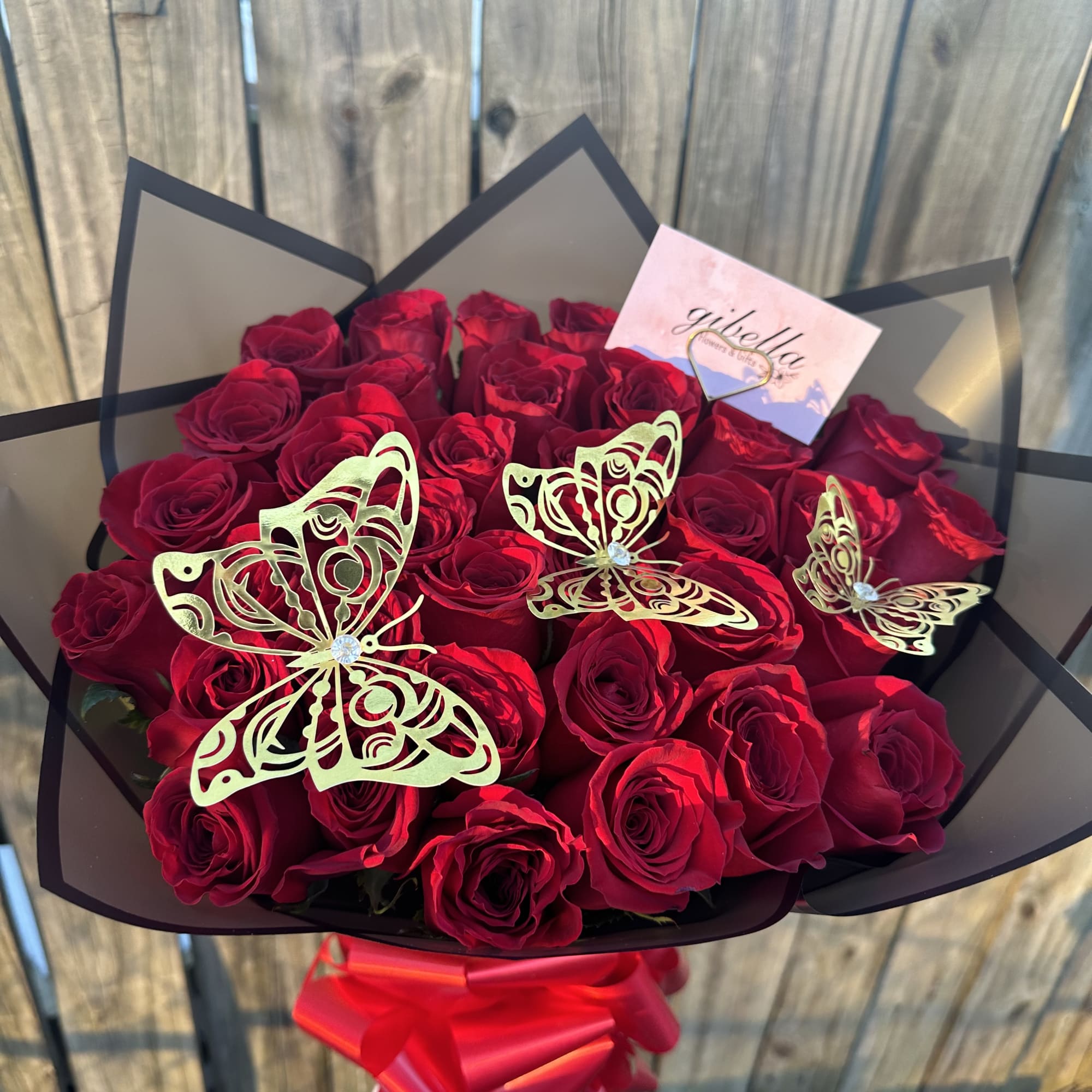 Bouquet of red roses with gold butterfly decorations and a red ribbon