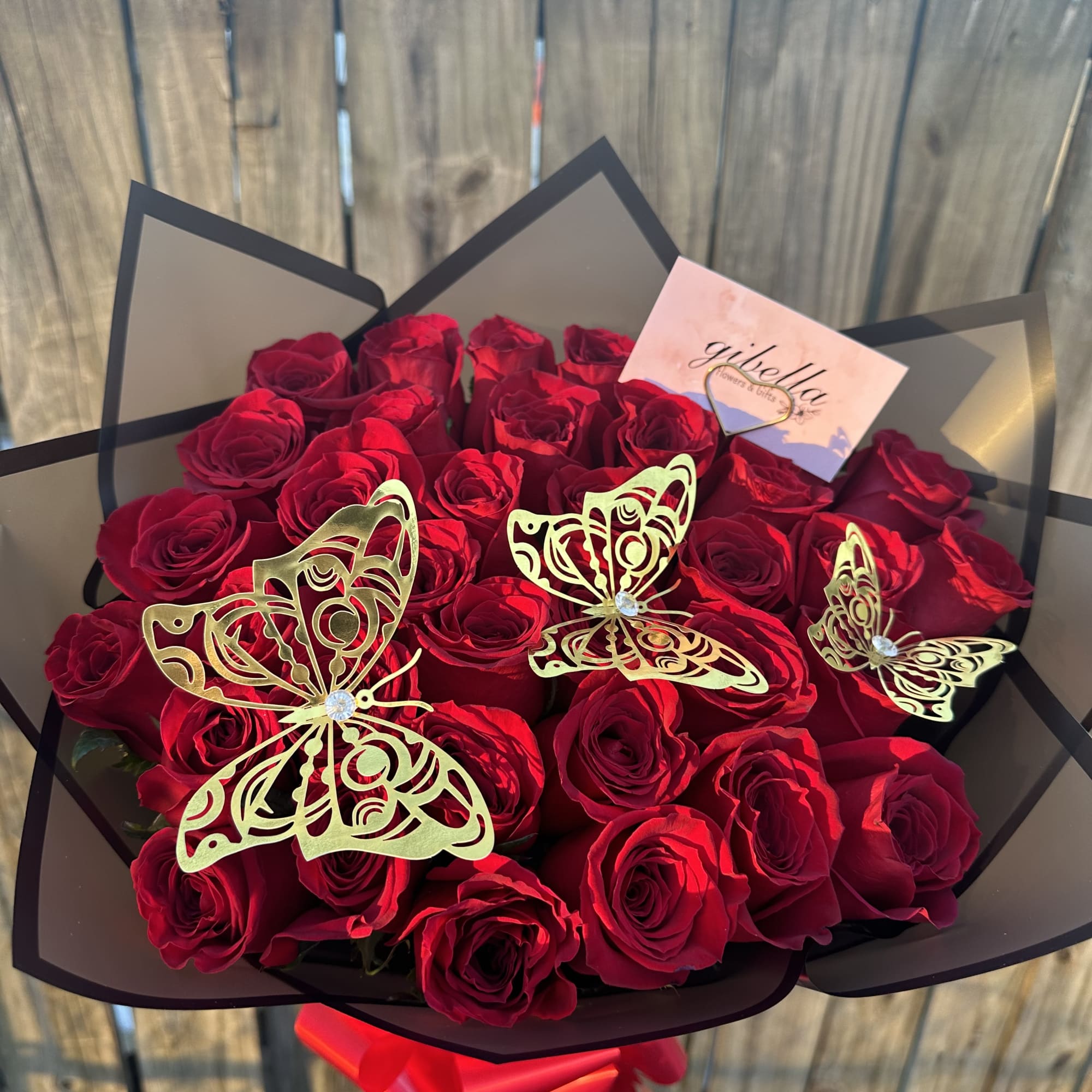 Bouquet of red roses with gold butterfly decorations and black wrapping