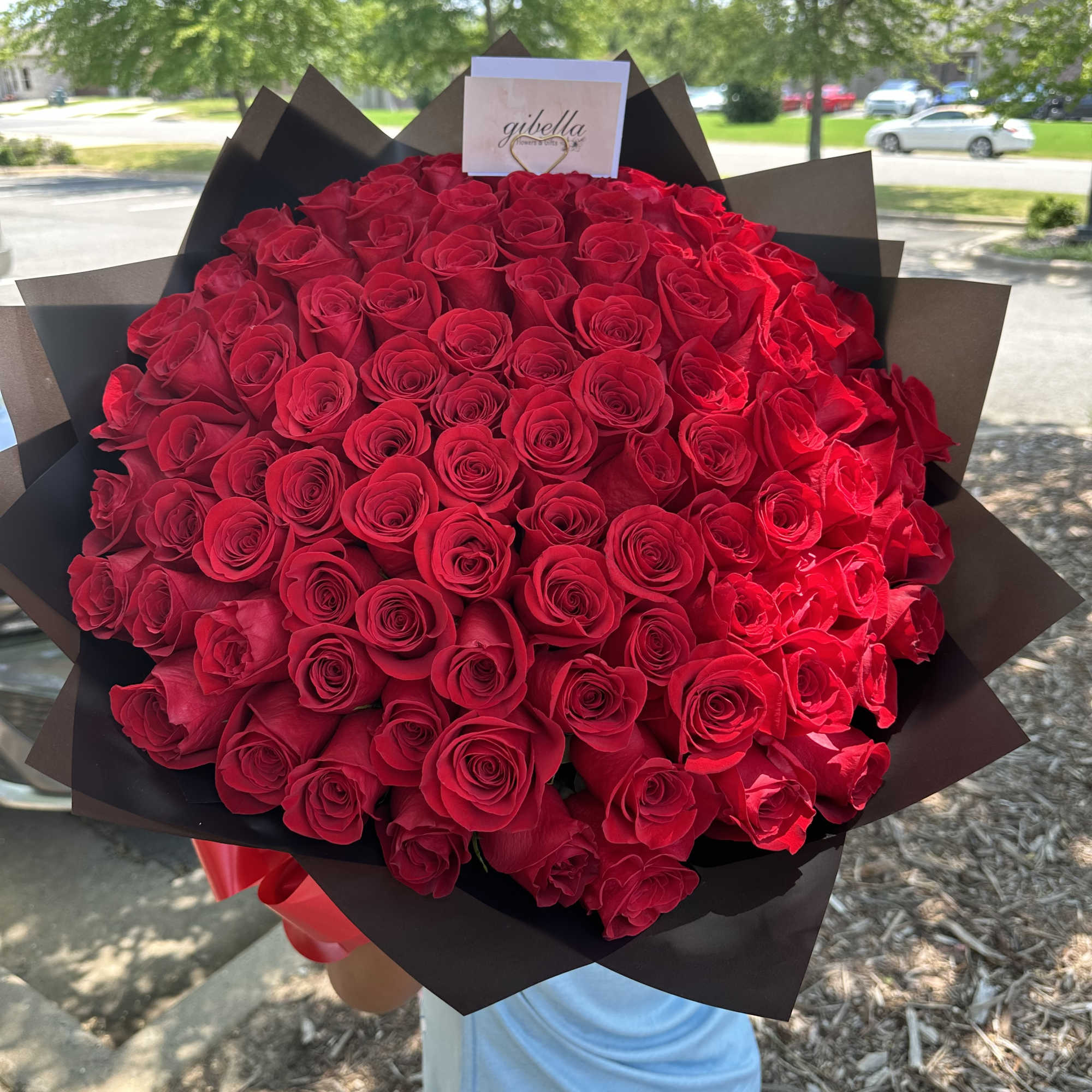 Large bouquet of red roses wrapped in dark paper