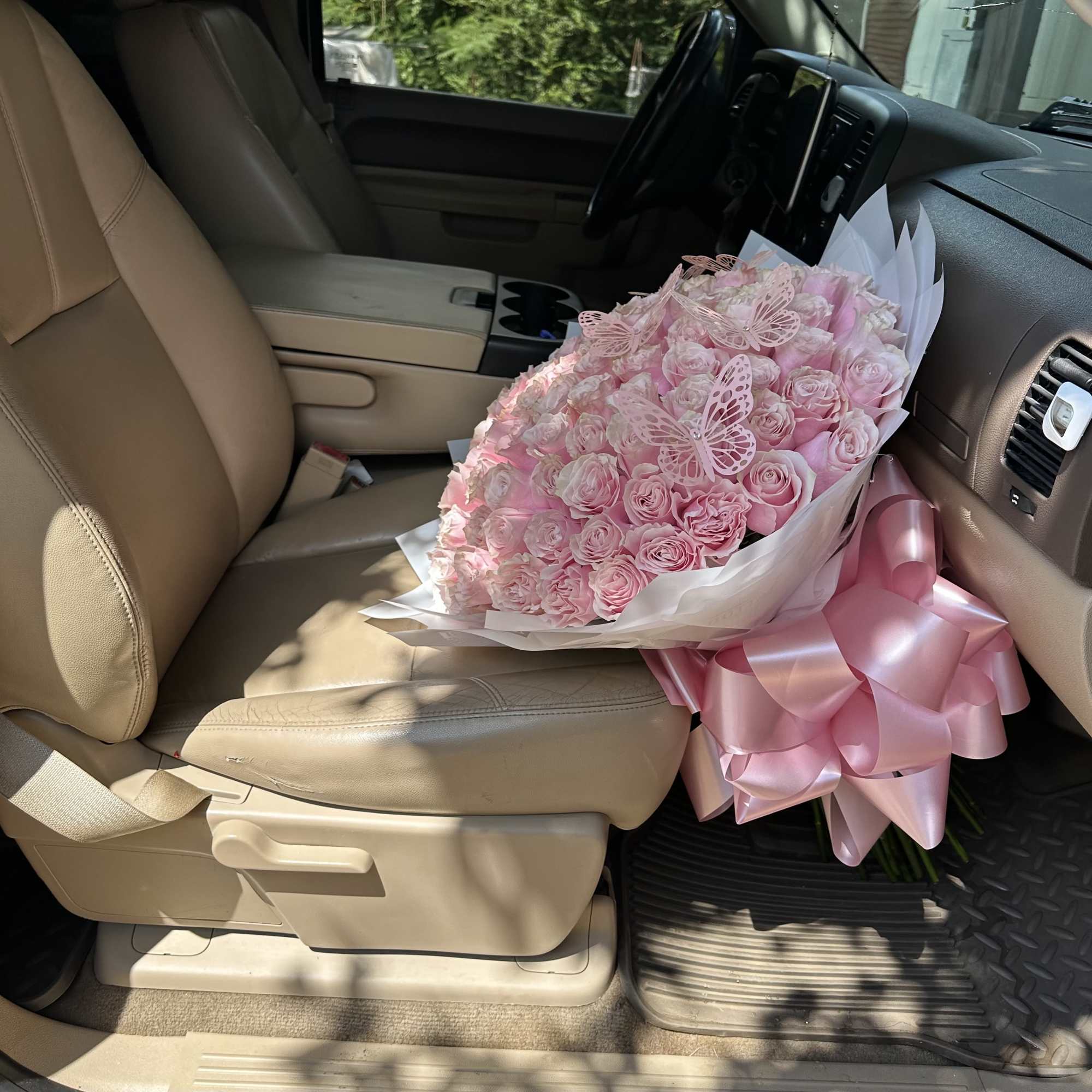 Large bouquet of pink roses with butterfly decorations in a car seat