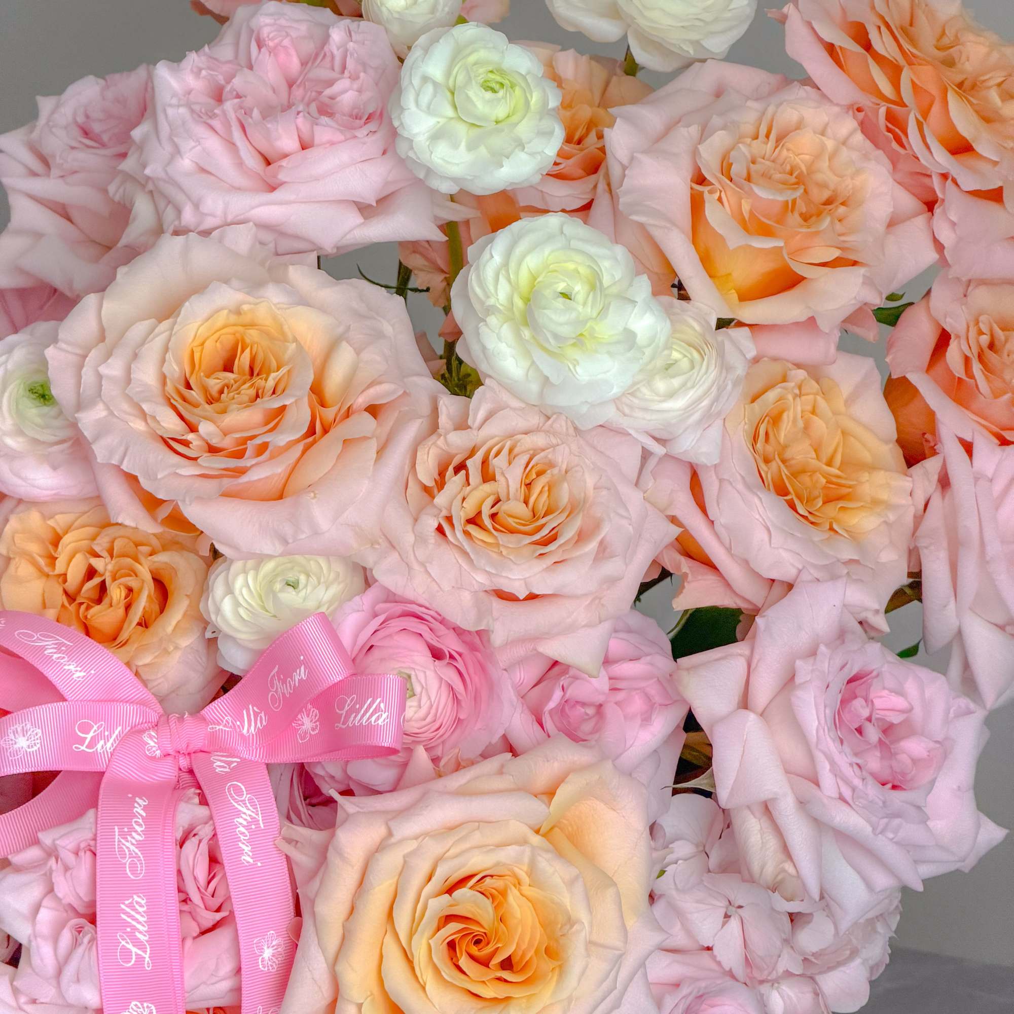 A lush, rounded arrangement in soft blush, peach, cream and pale orange-perfect
