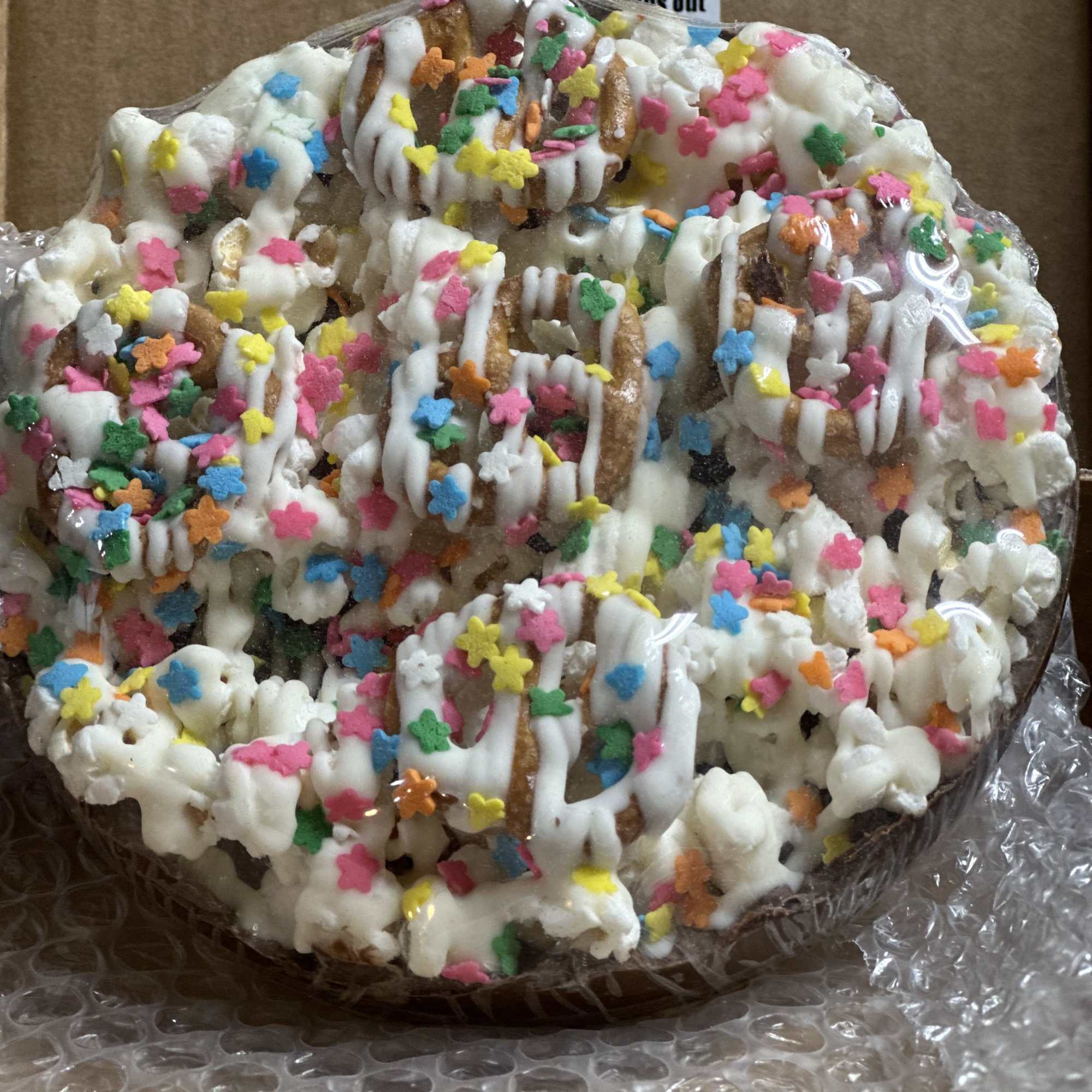 Round pastry topped with white icing and colorful sprinkles