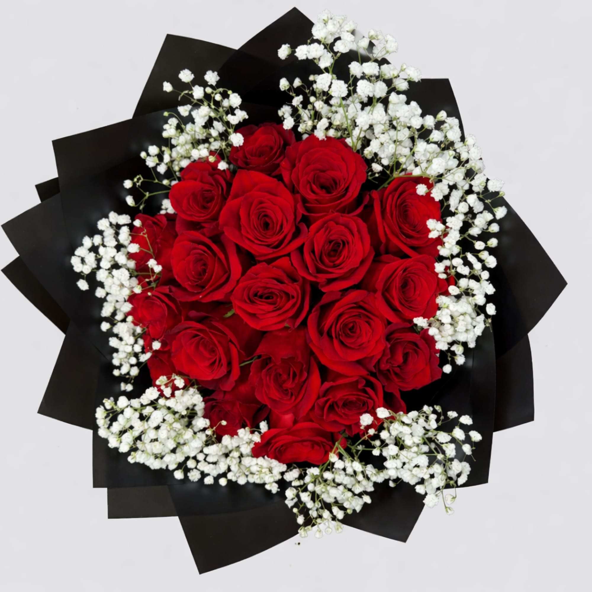 Round bouquet of red roses and white filler flowers wrapped in black paper.