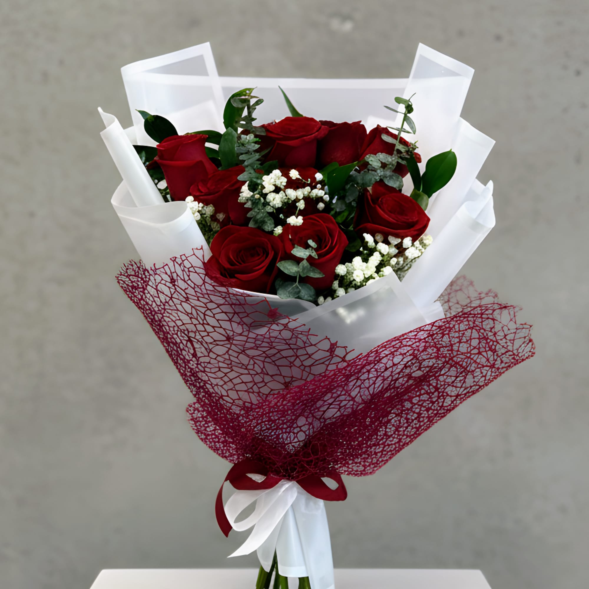 Bouquet of red roses wrapped in white and burgundy paper