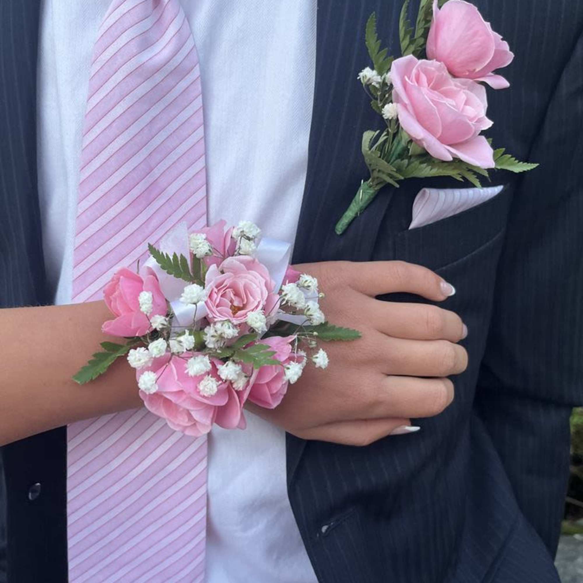 Soft pink roses arranged in a compact, rounded corsage set create a