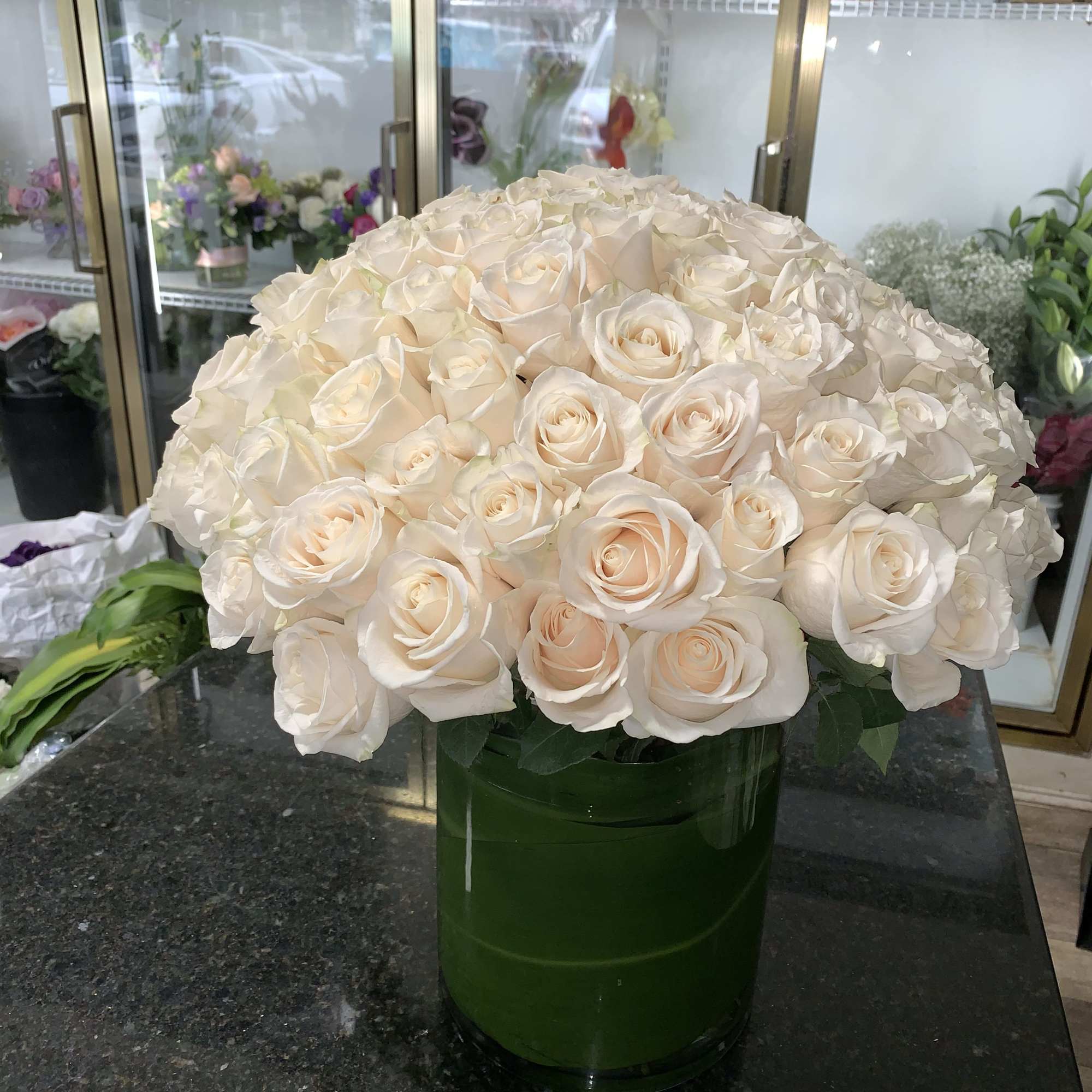 Large bouquet of cream roses in a green glass vase