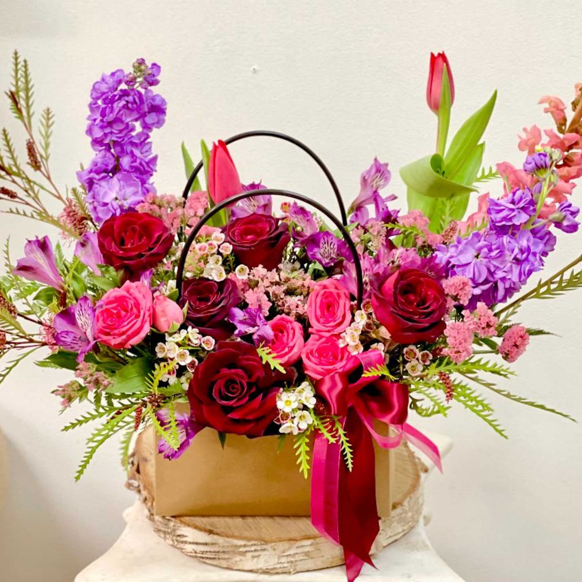 Mixed bouquet of red and pink roses with purple flowers in a gift box