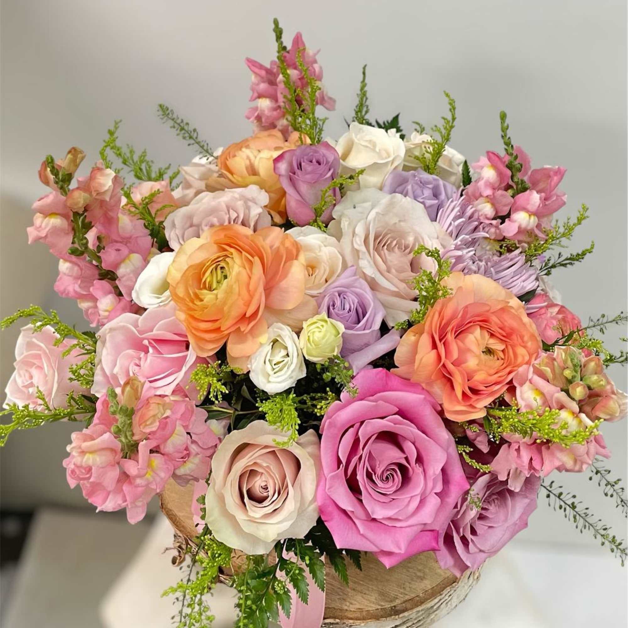 Mixed bouquet of pastel roses and pink snapdragons in a rustic box