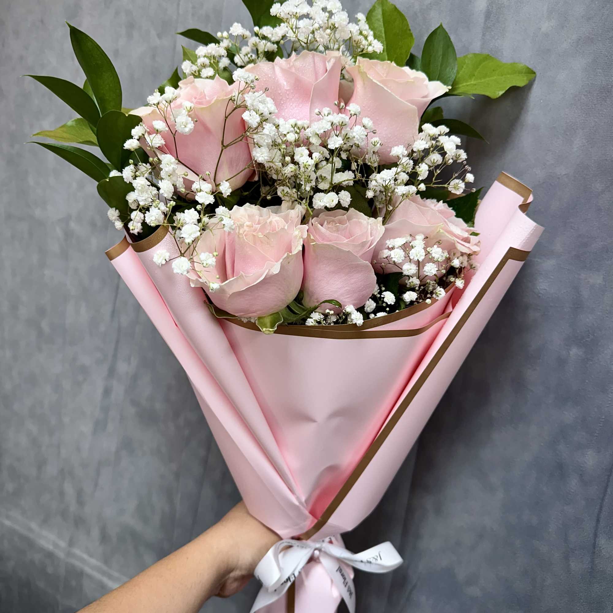 Bouquet of pale pink roses with white baby's breath in pink wrapping