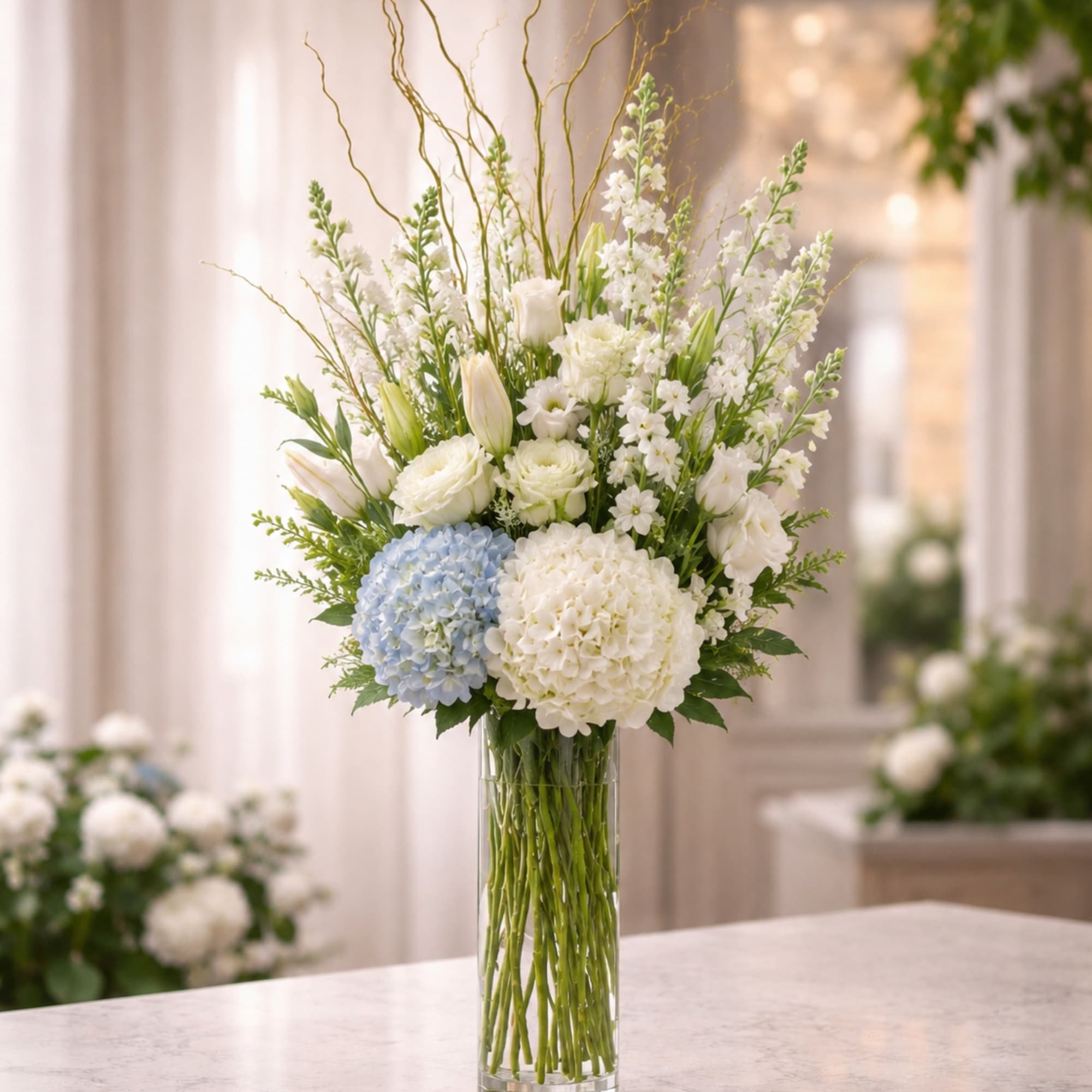 A graceful and elevated arrangement featuring soft white blooms, delicate seasonal florals