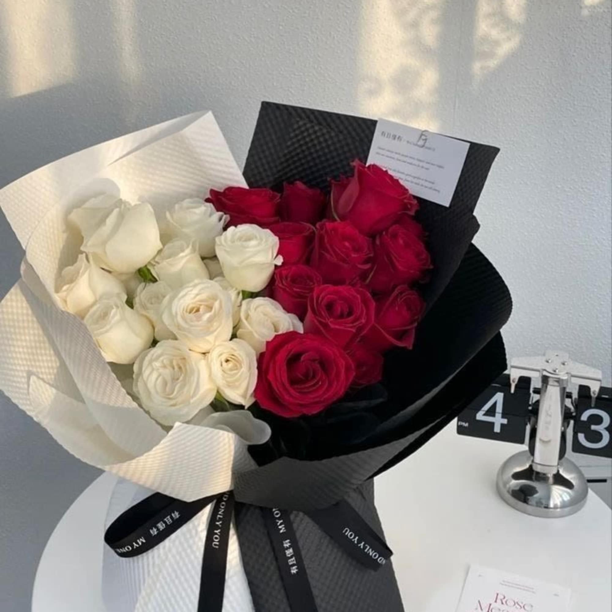 Bouquet of red and white roses wrapped in black and white paper