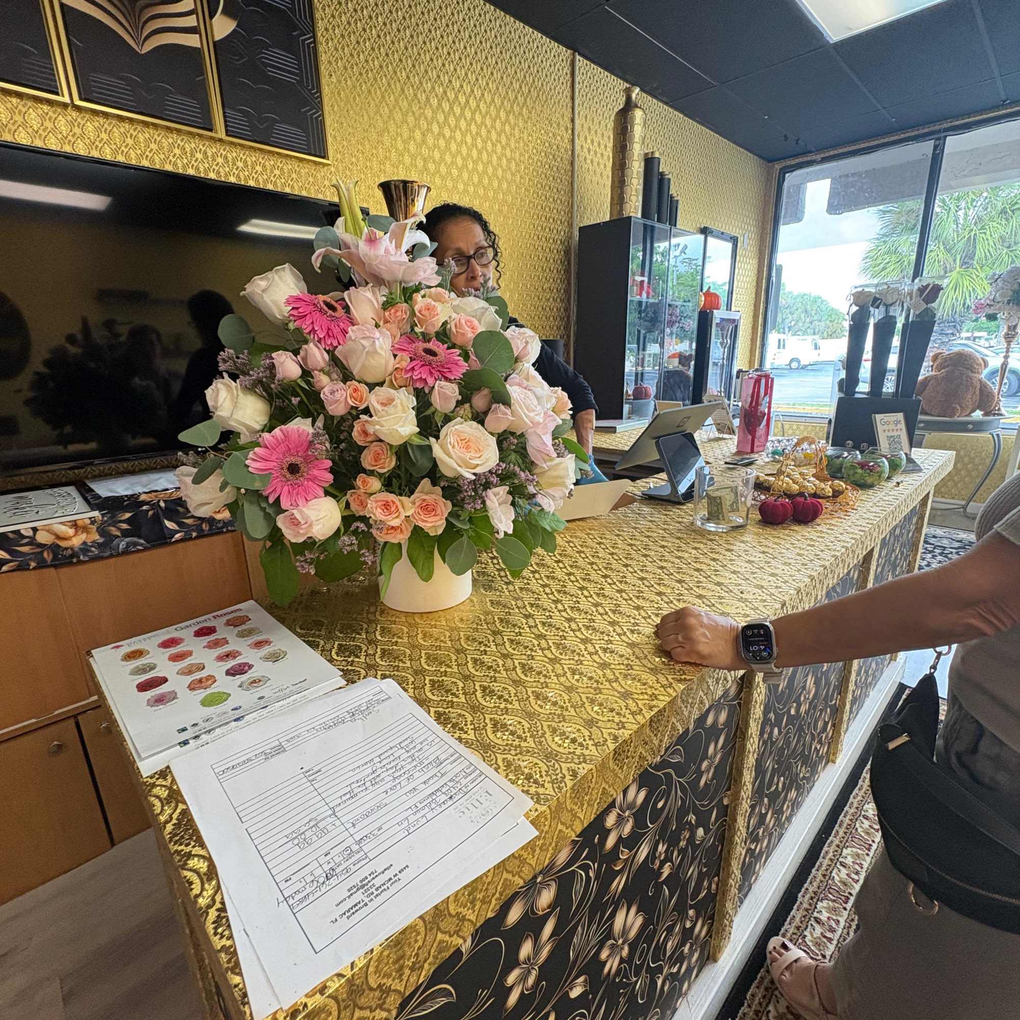 Large pink and white floral arrangement in a white vase on a counter