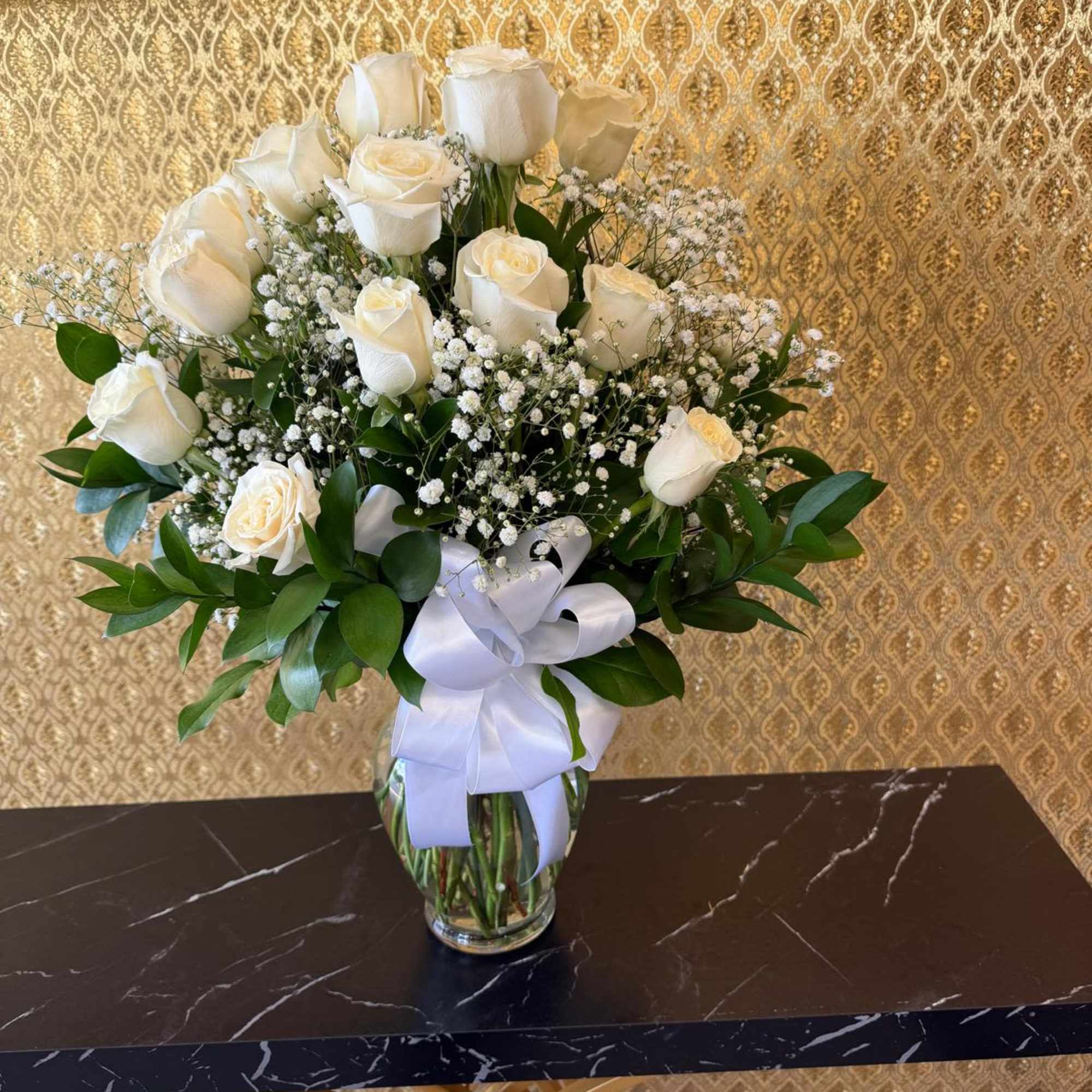 White rose bouquet in a glass vase with a white ribbon
