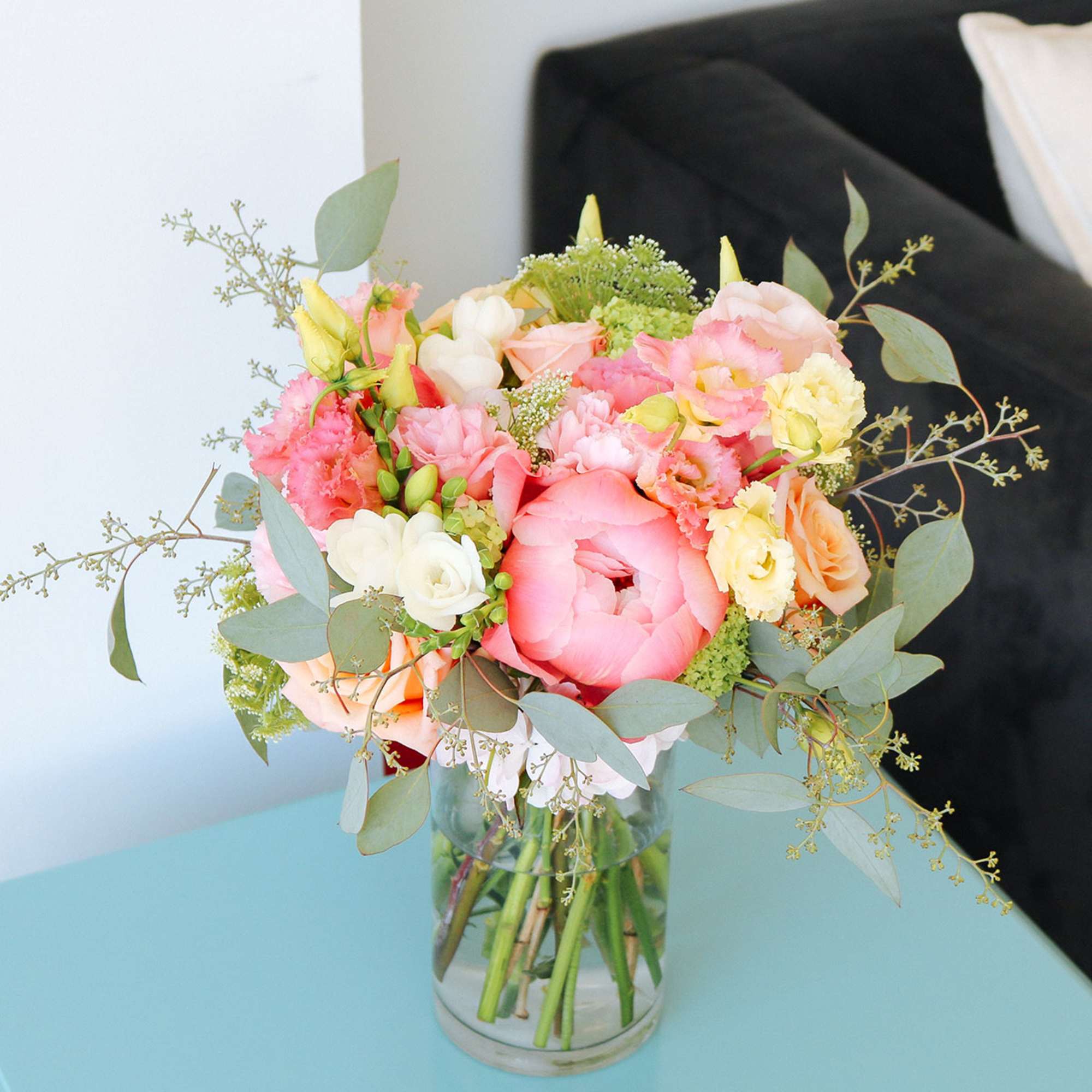 Mixed bouquet of pink and peach flowers with white blooms in a clear glass vase