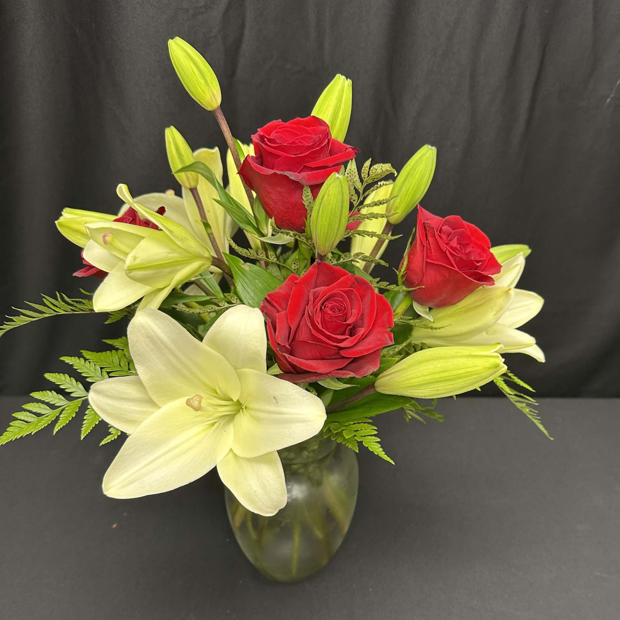 Red roses and white lilies arranged in a glass vase