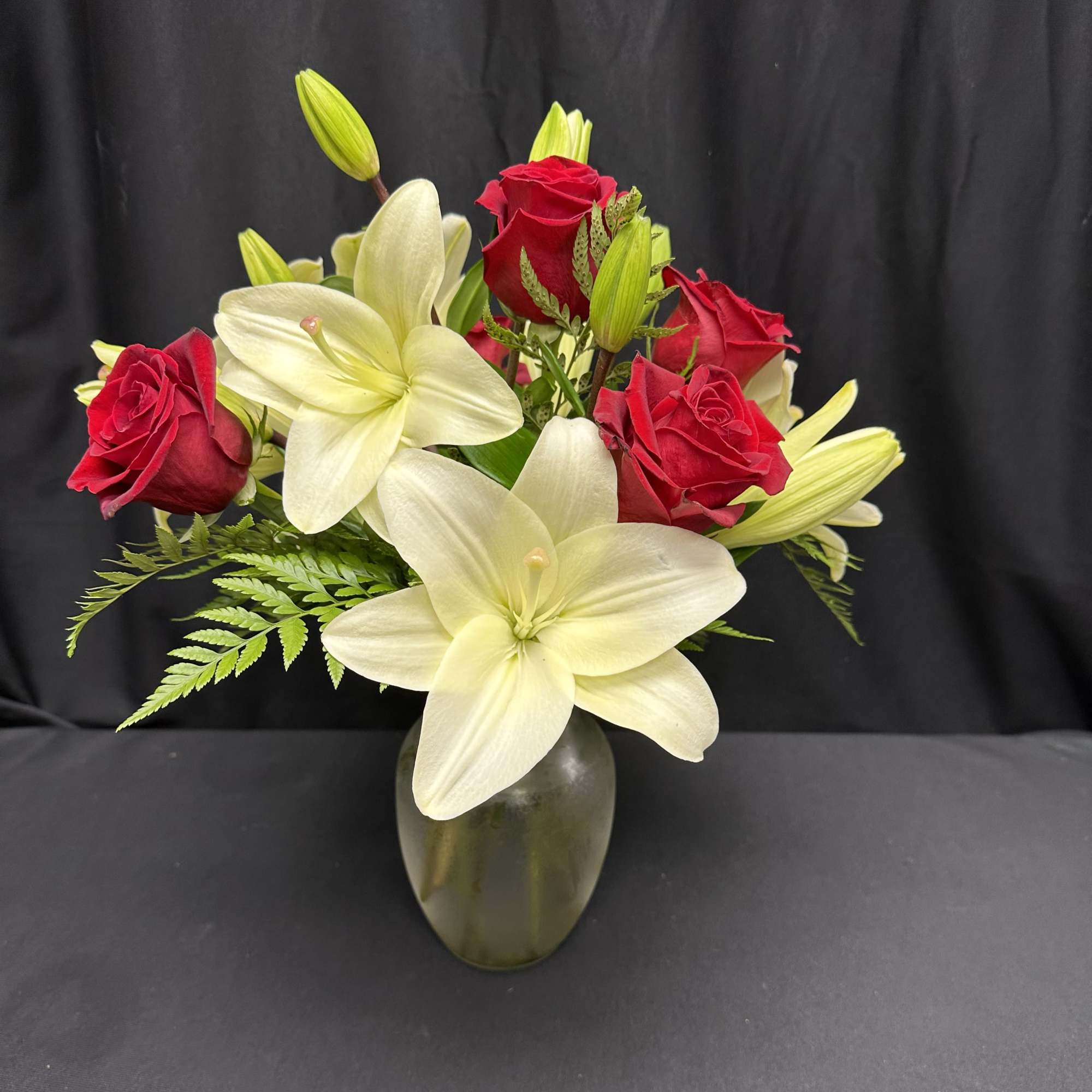 Red roses and white lilies arranged in a glass vase