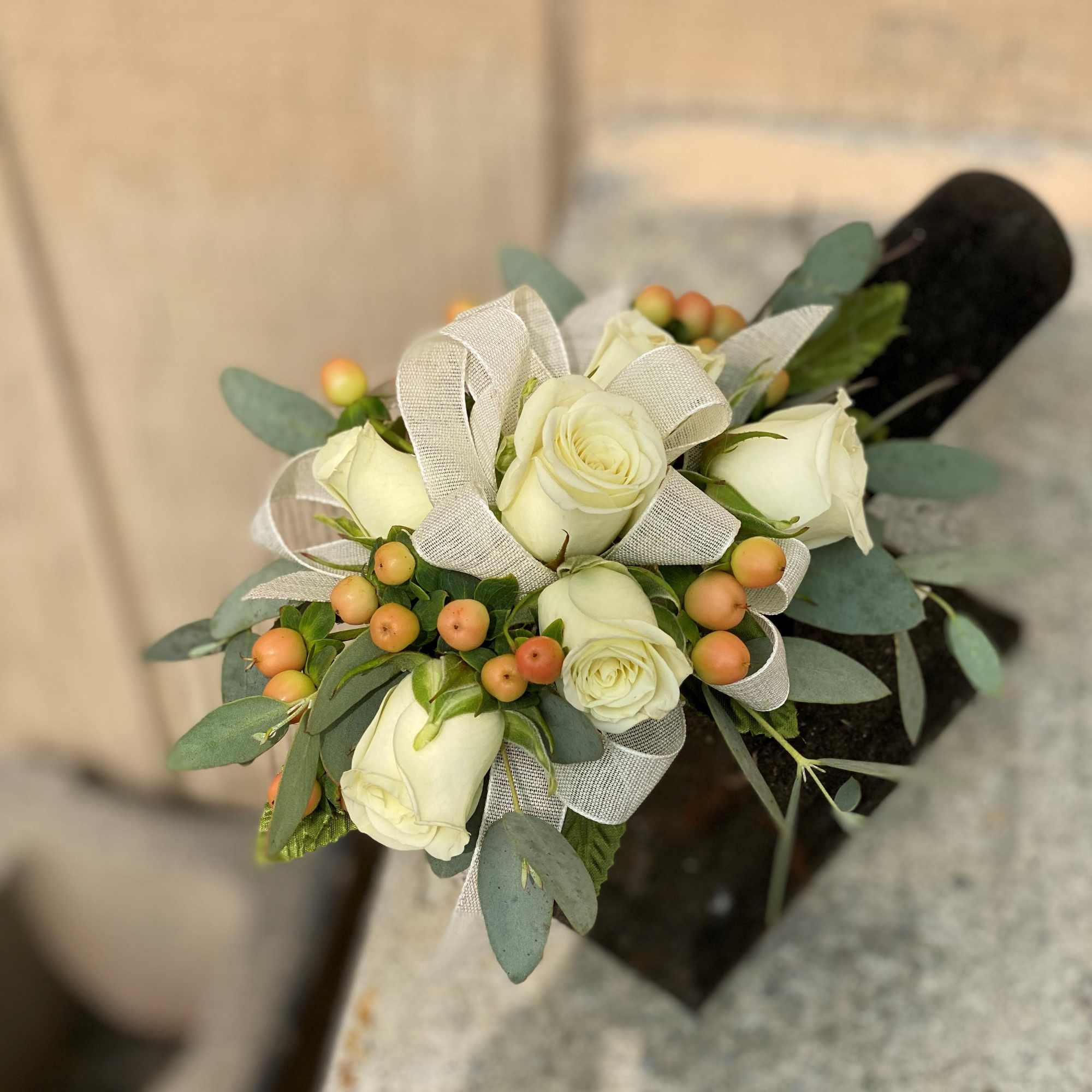 This wrist corsage is made up of white spray roses, peach hypericum